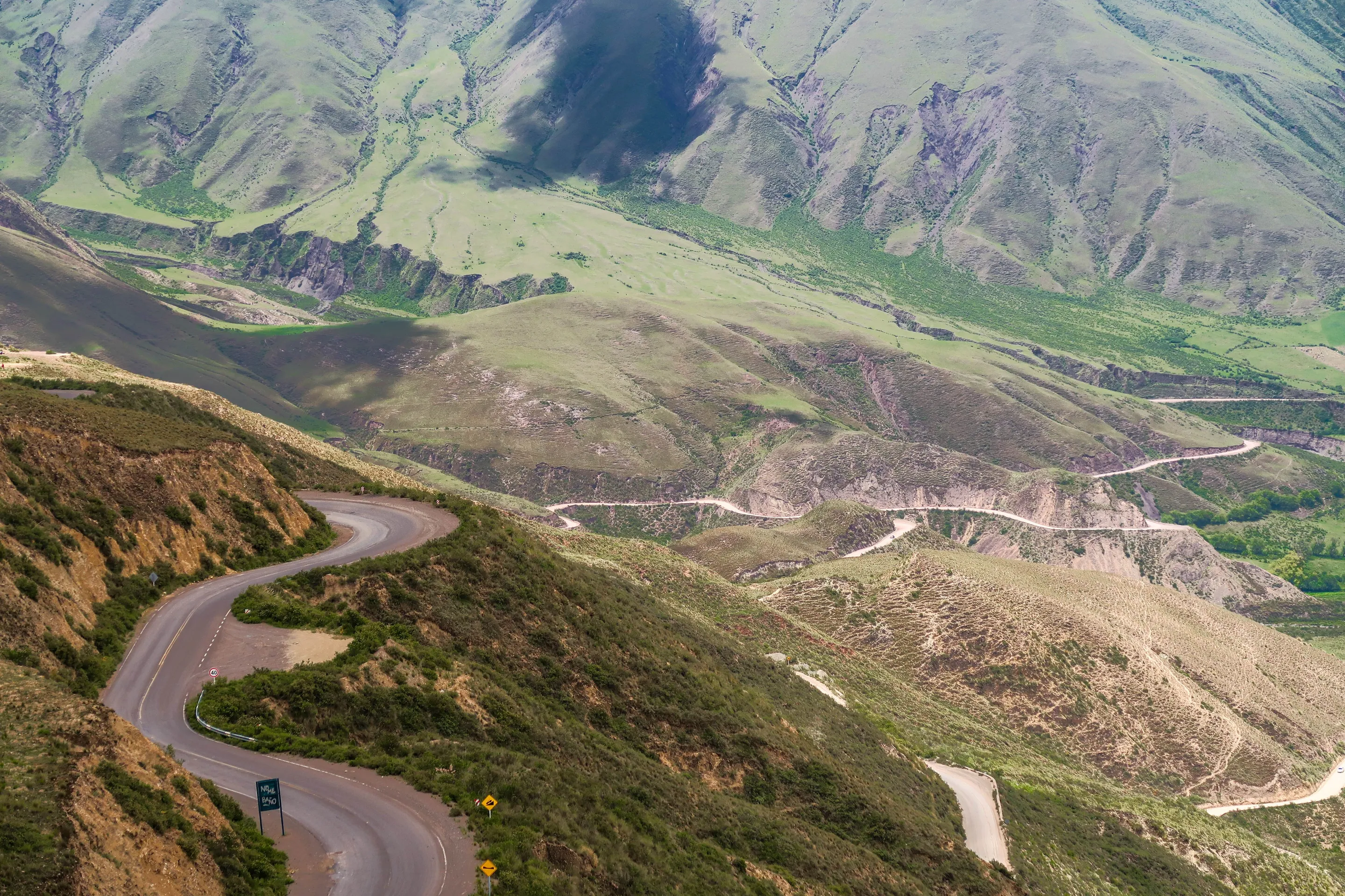A winding mountain road through the green hills of Salta.