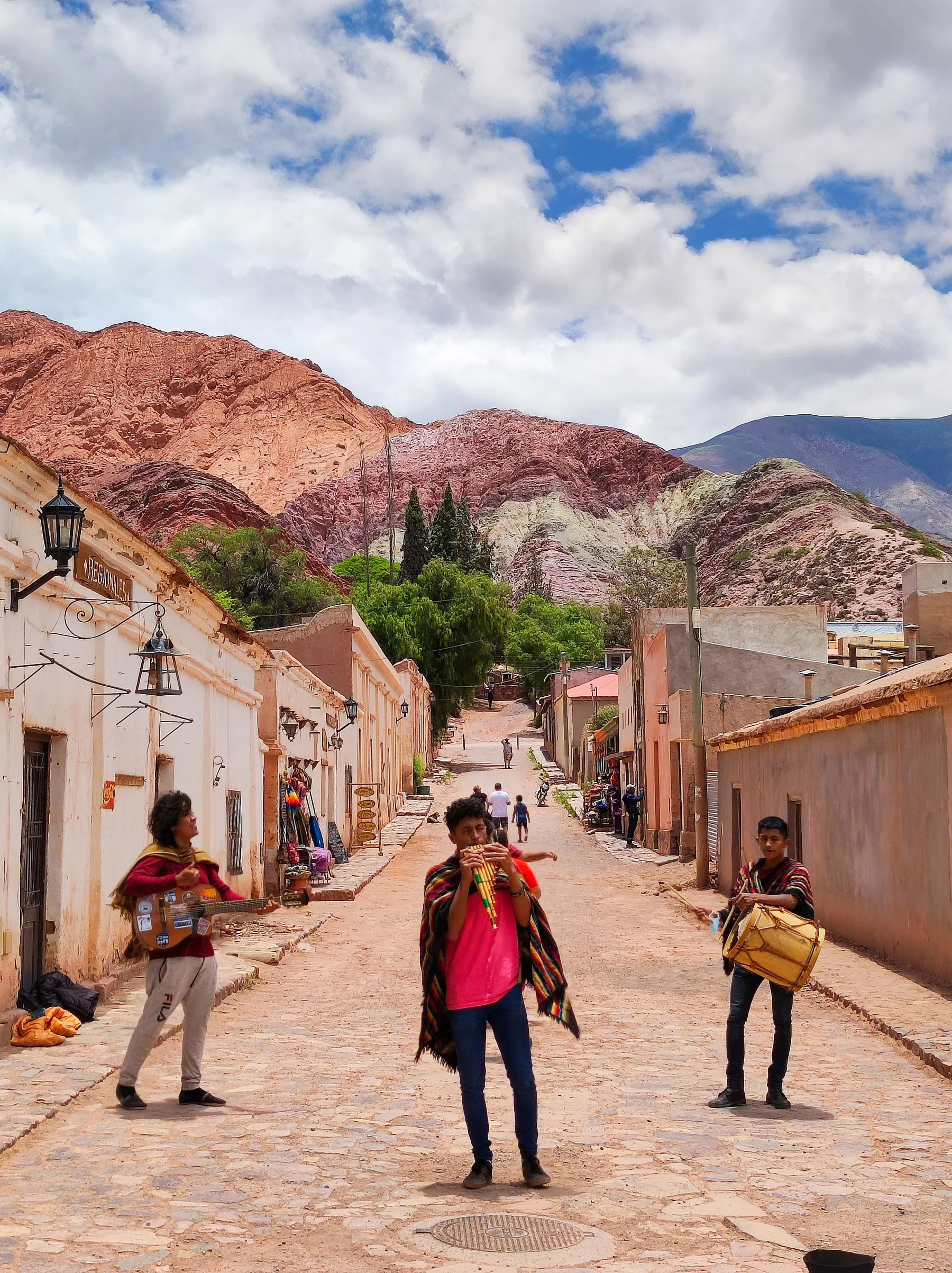Musicians playing in a Tilcara street beneath the hills