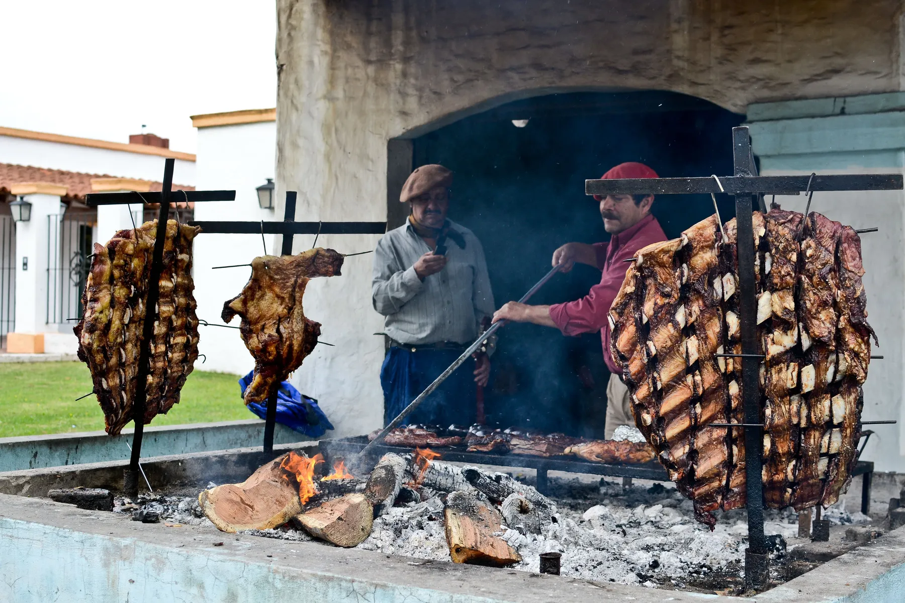 Men tending an Argentine asado over an open fire