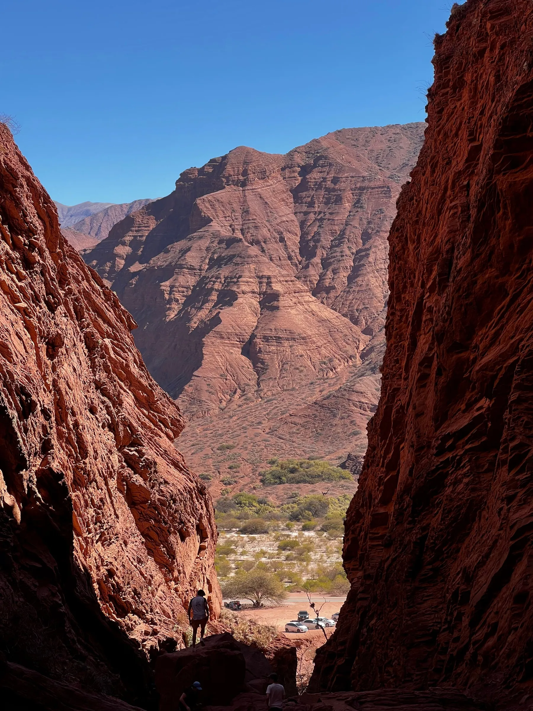 A person dwarfed by towering red sandstone formations in Salta