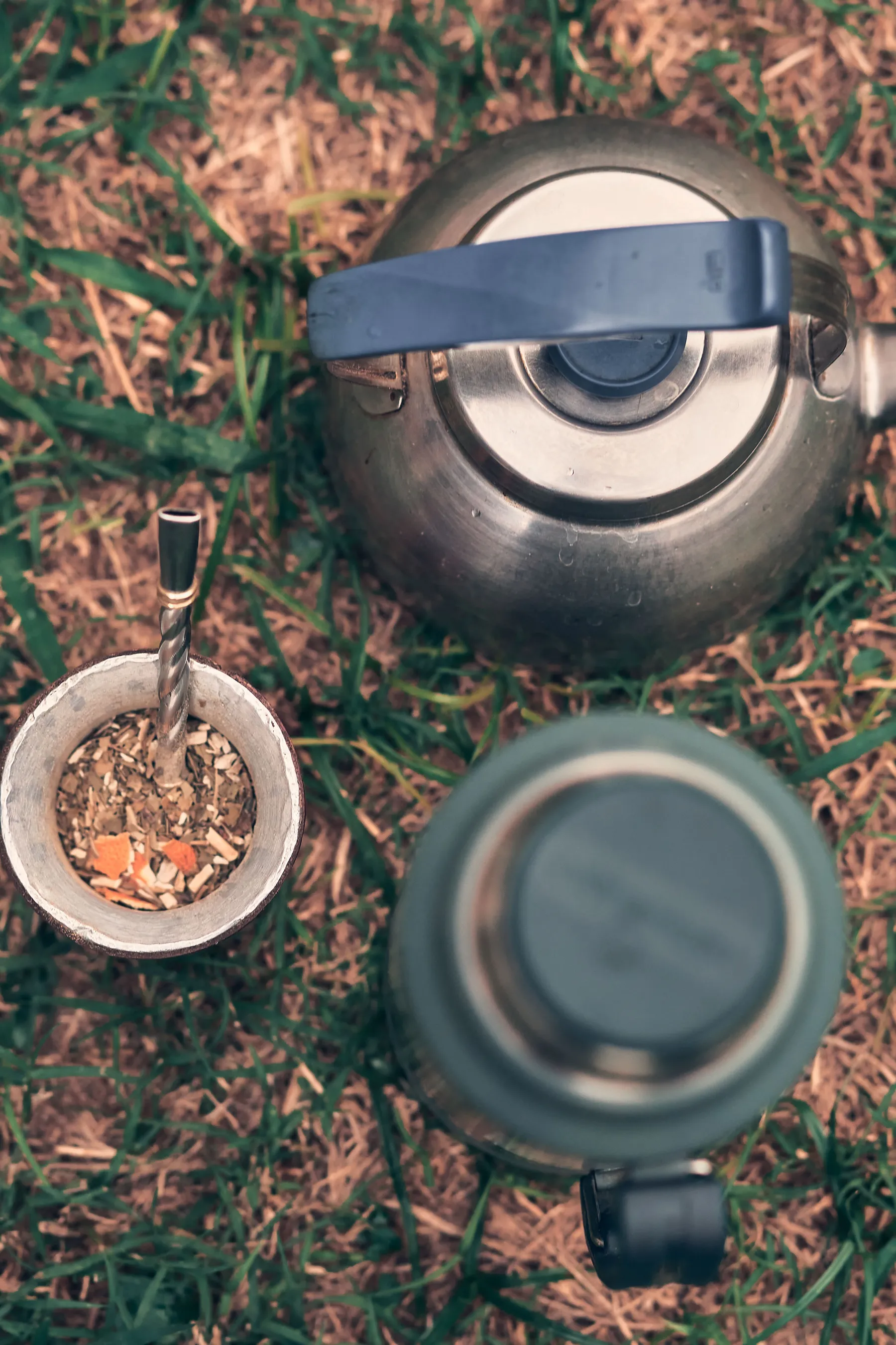 A mate gourd, kettle and thermos arranged on grass