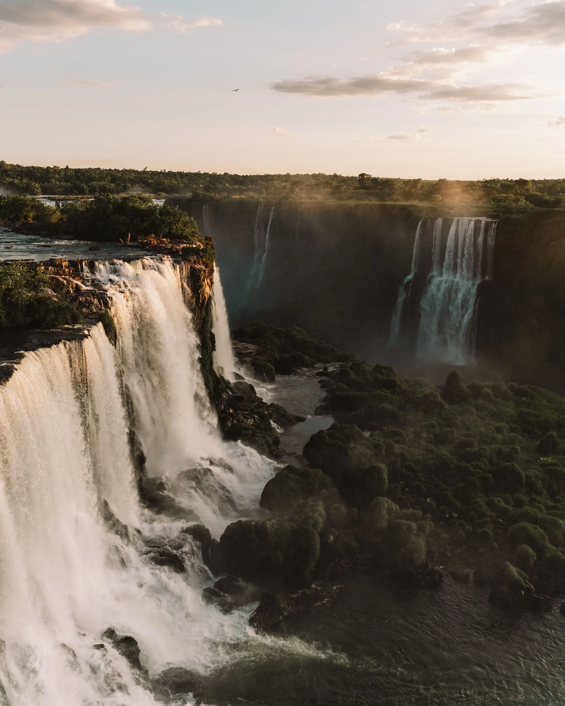 Iguazú Falls cascading beneath a dramatic cloudy sky at sunset
