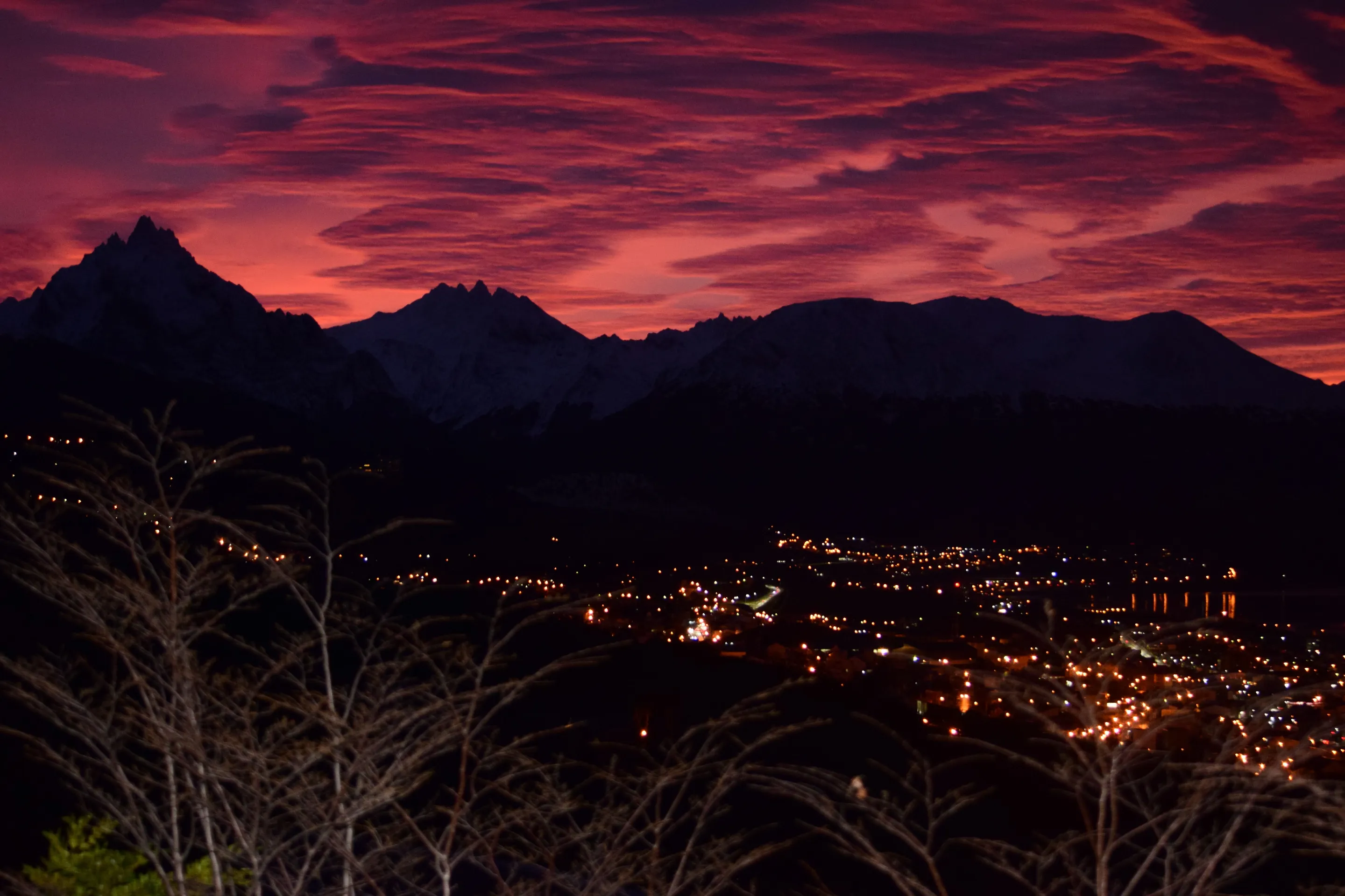 Ushuaia's lights beneath mountains and a vivid twilight sky.