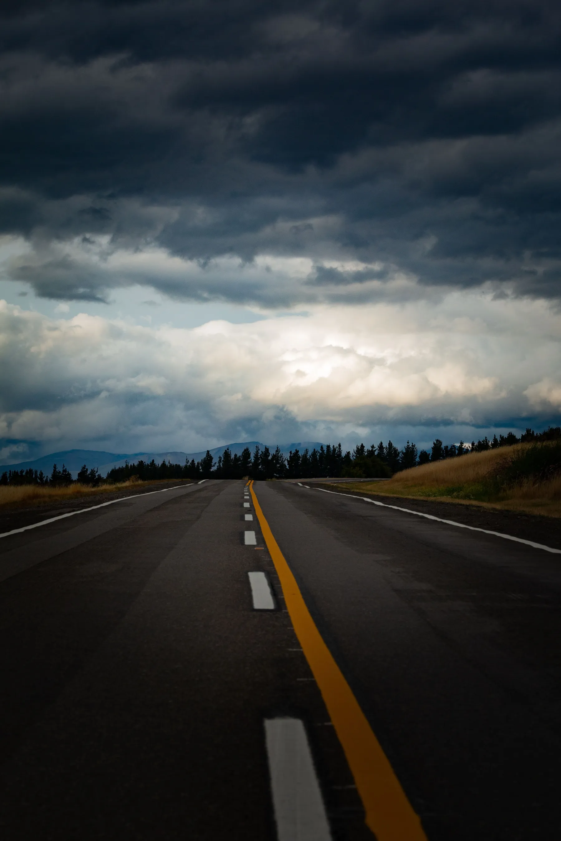 A road towards the Trevelin mountains beneath dramatic dark clouds