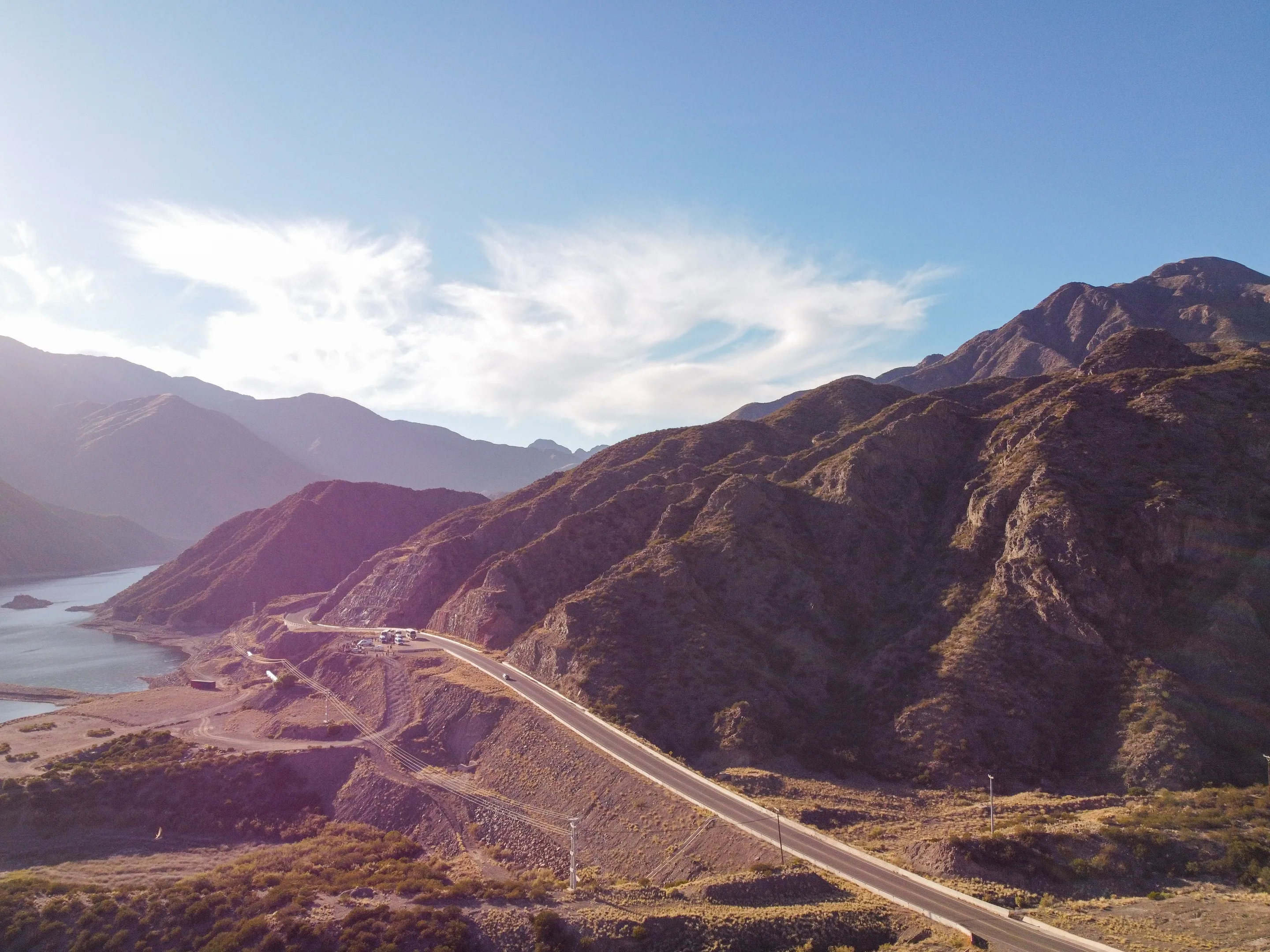 A highway curves beside a blue reservoir through Mendoza's dry mountains