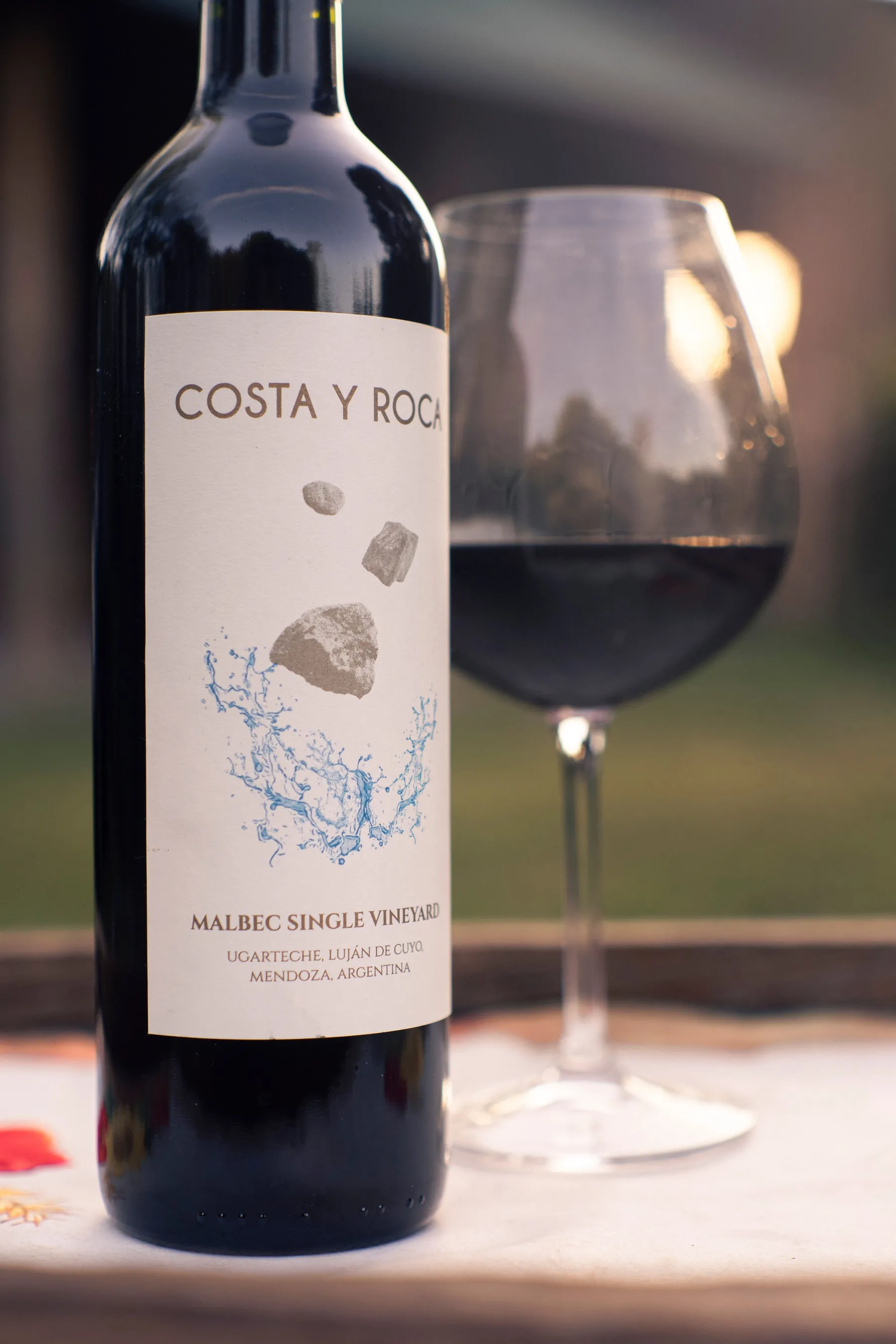 A Malbec bottle and wine glass lit by the setting sun in Luján de Cuyo