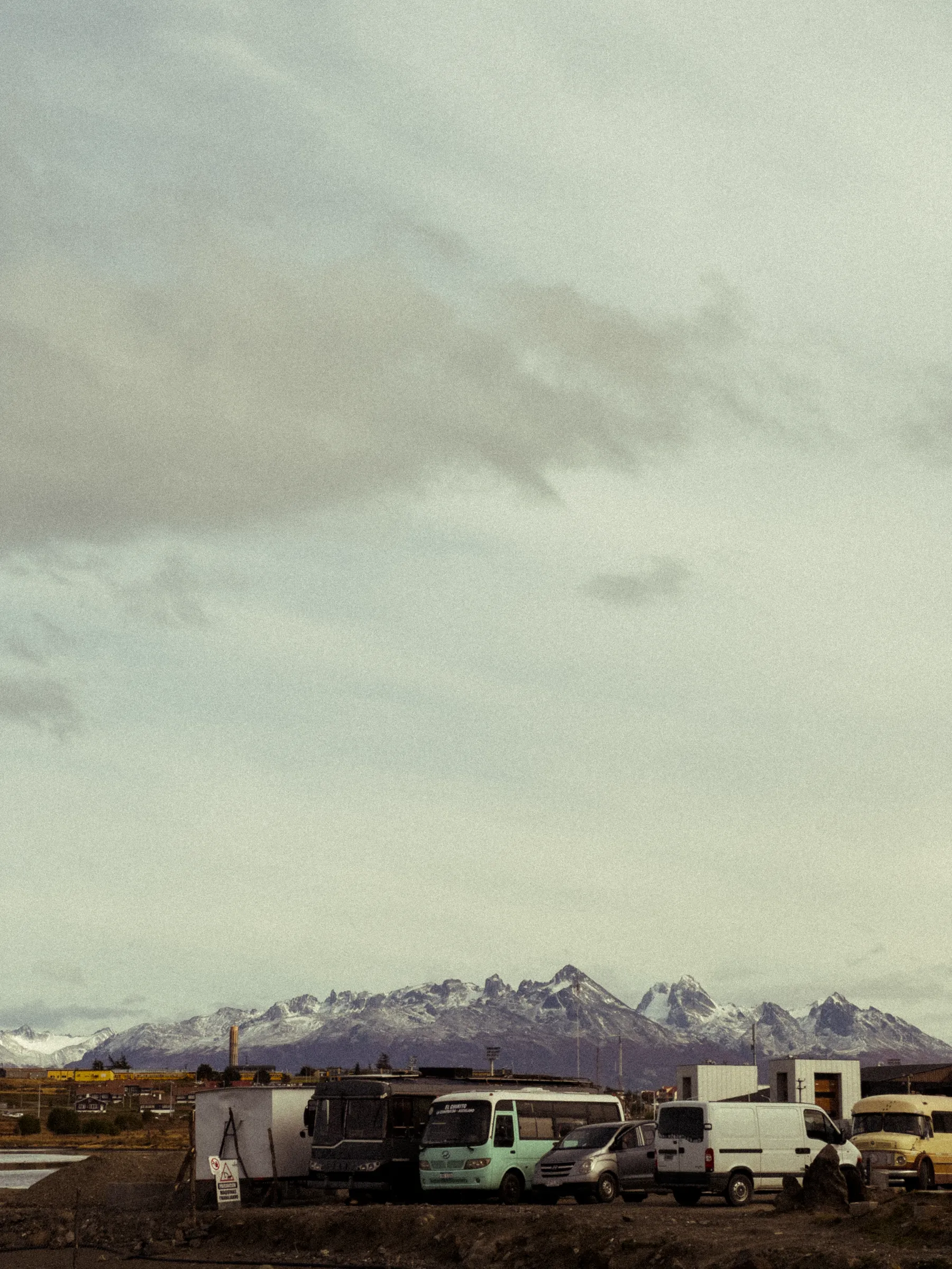Vehicles below the snow-covered mountains near Ushuaia.