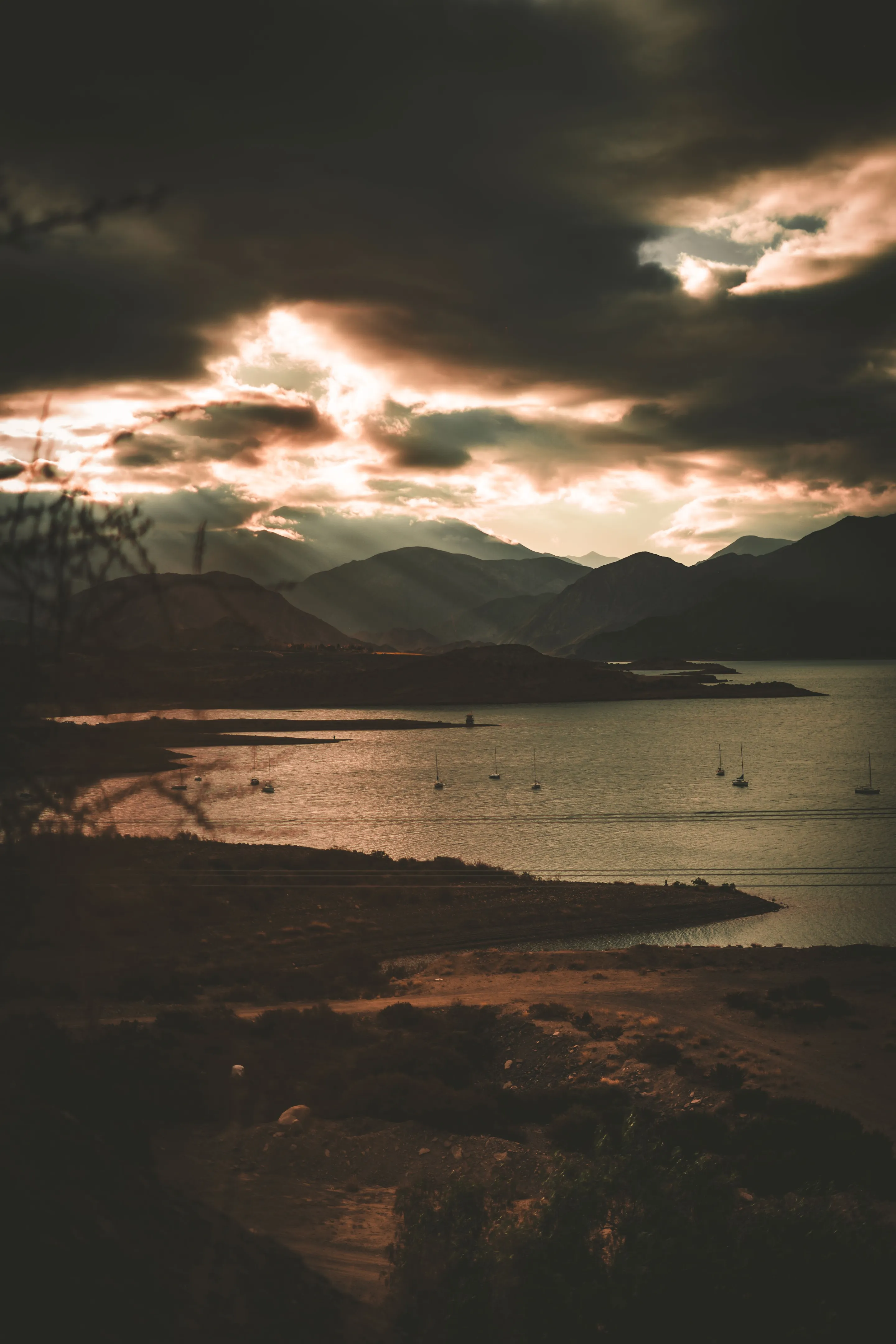 Mountain silhouettes and dramatic sunset clouds over Potrerillos Lake