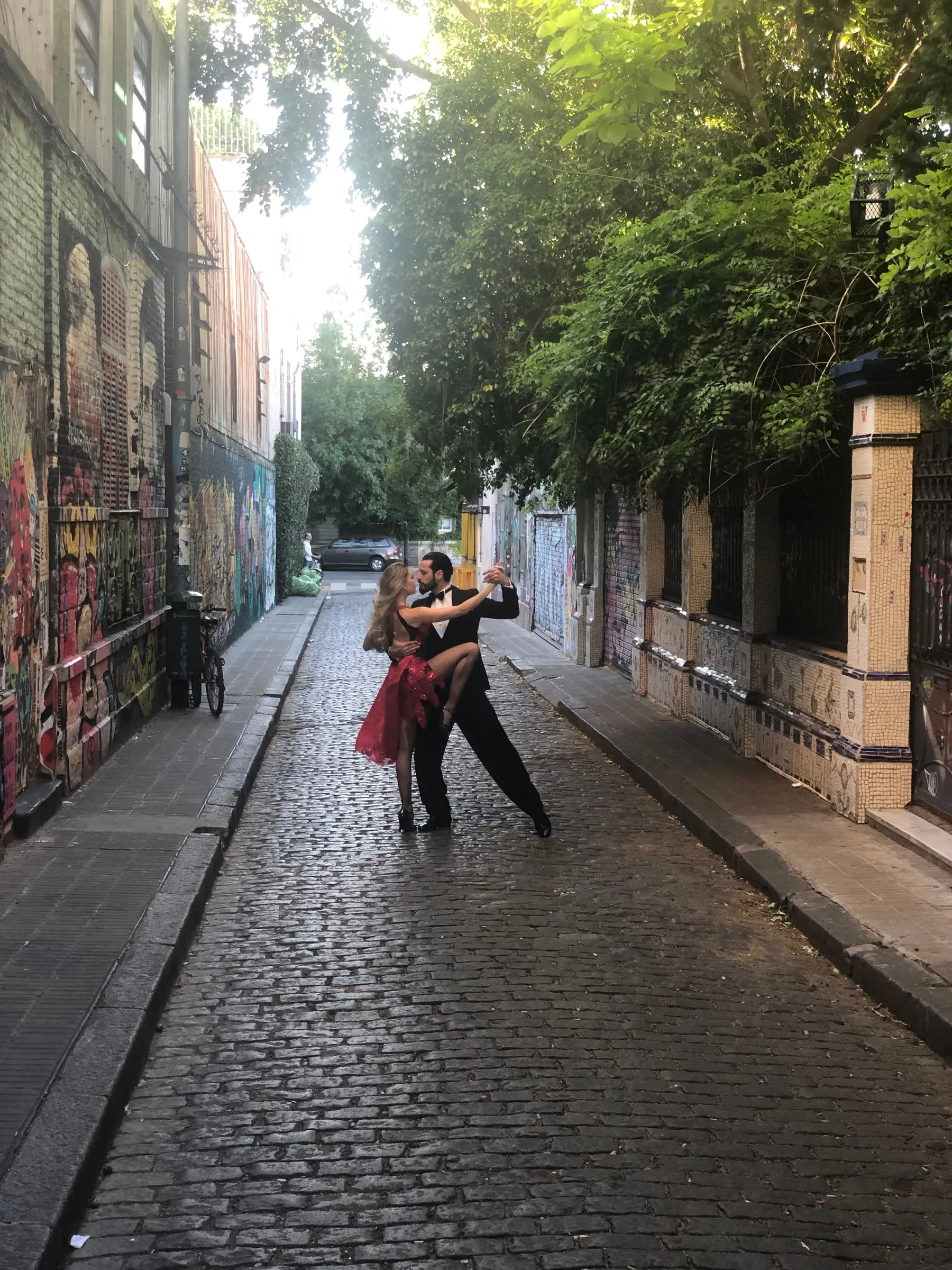 A couple dancing tango on a colourful cobblestone street.