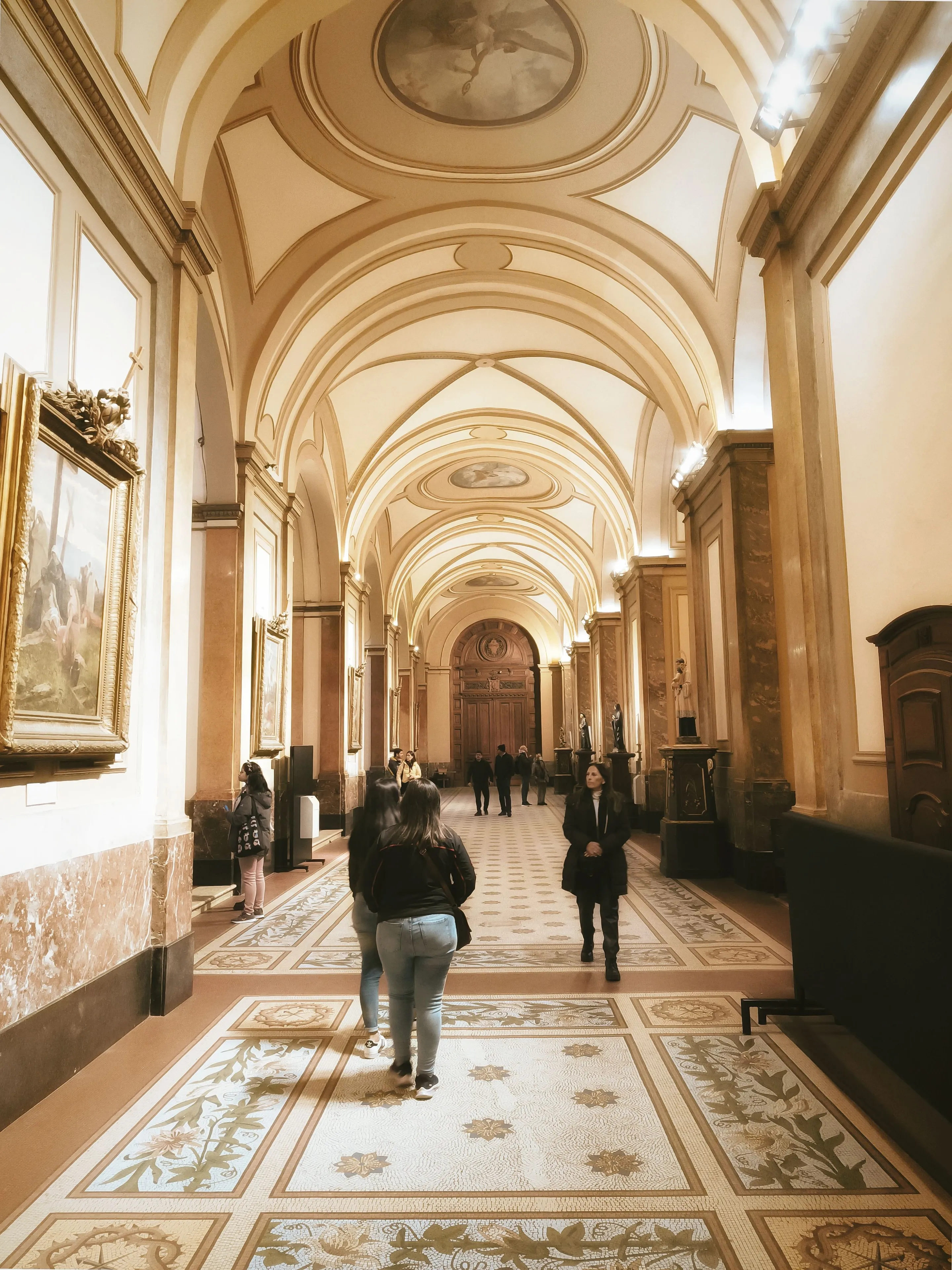 Visitors beneath the arches of a Buenos Aires museum corridor.