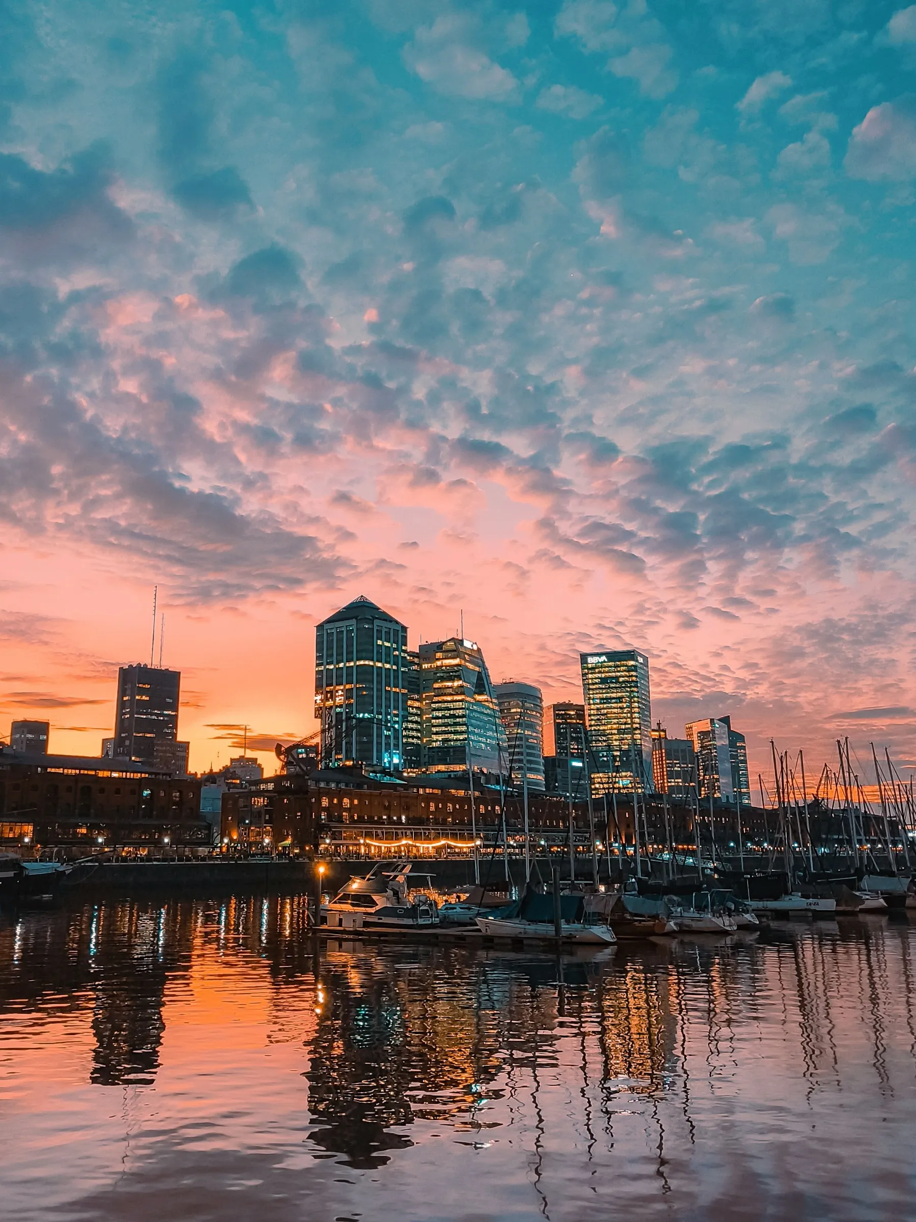 Glowing sunset clouds reflected around the Puerto Madero skyline