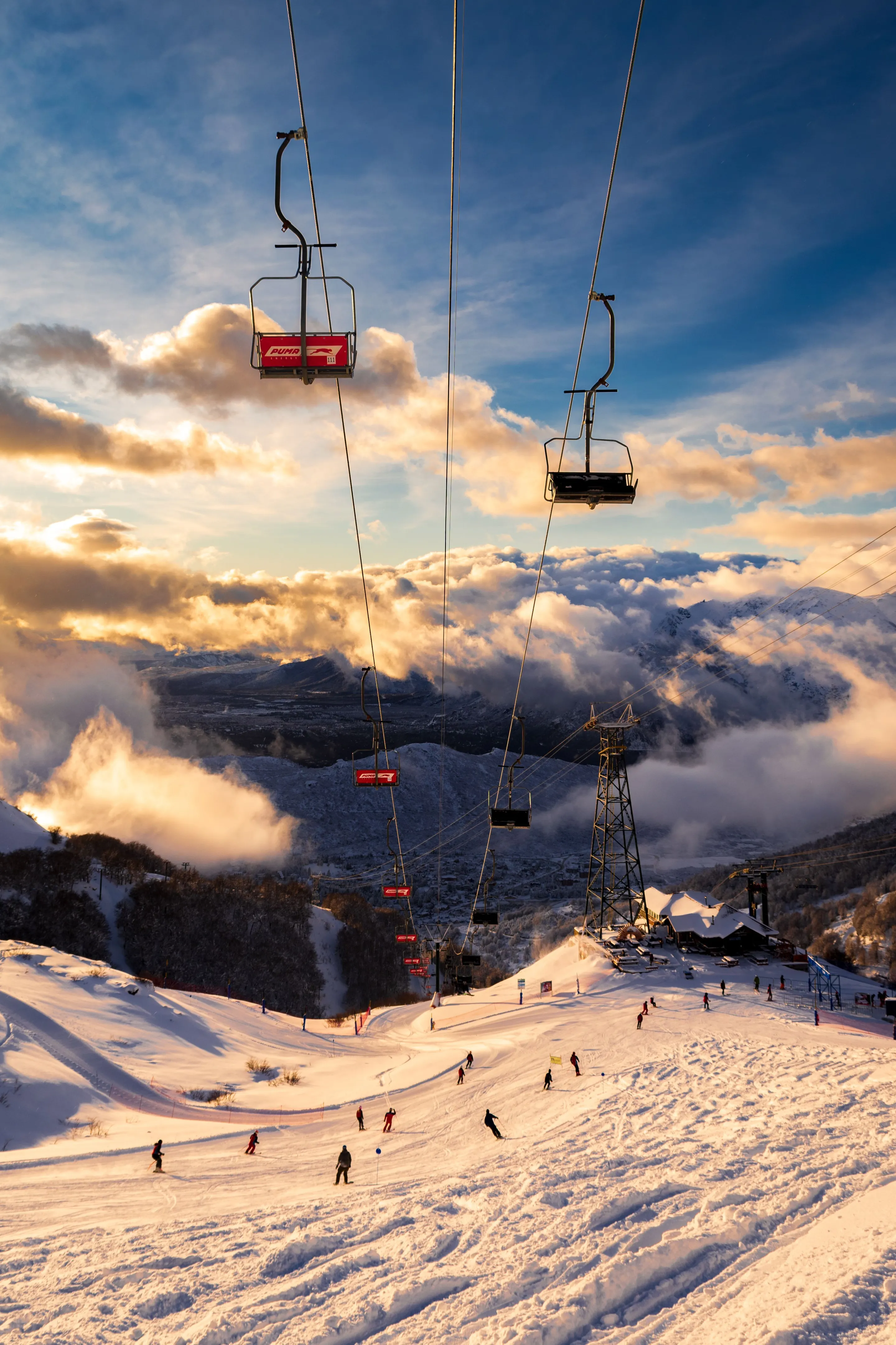 Skiers on a snowy mountain beneath warm winter light.