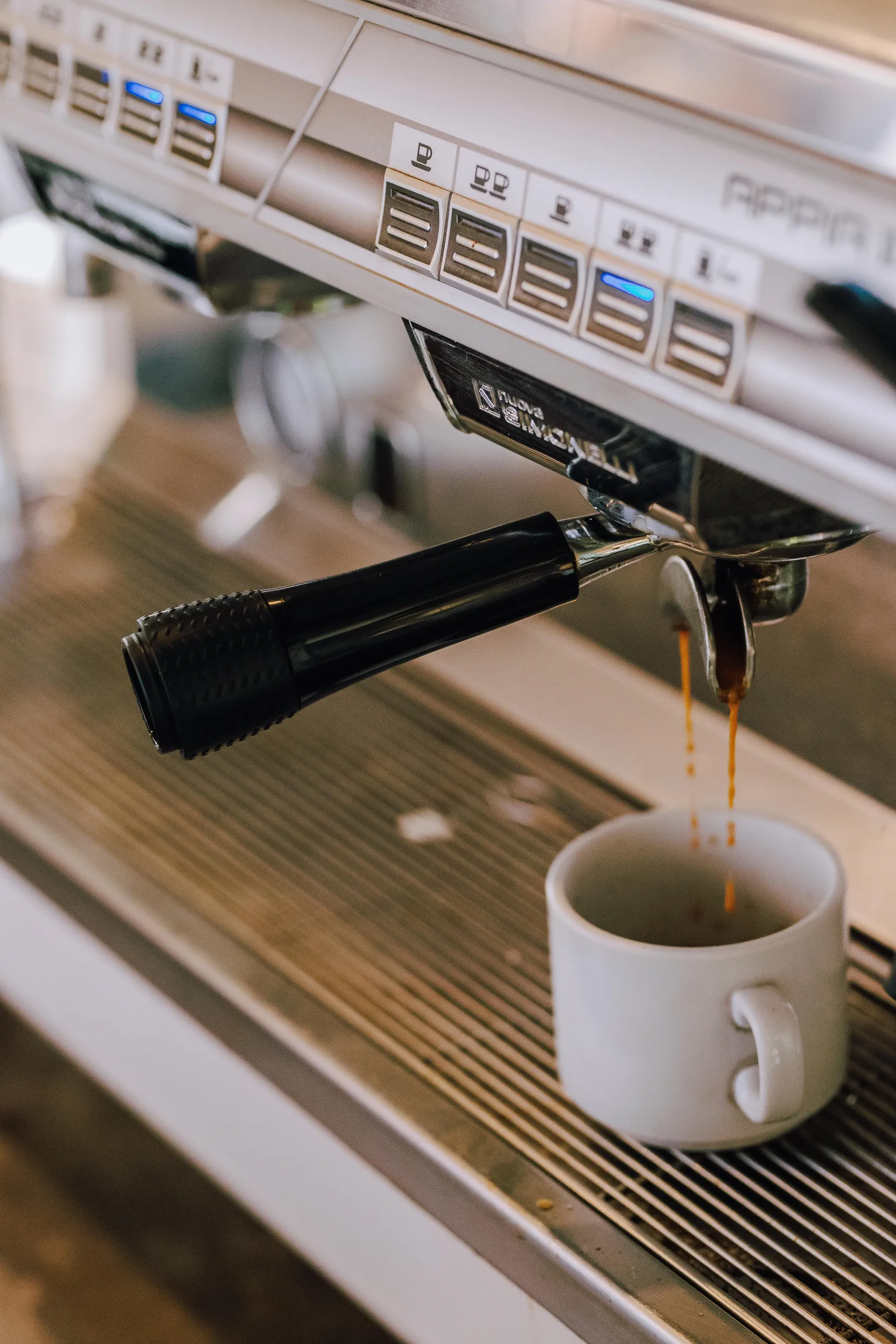 Espresso pouring into a cup beneath a café coffee machine