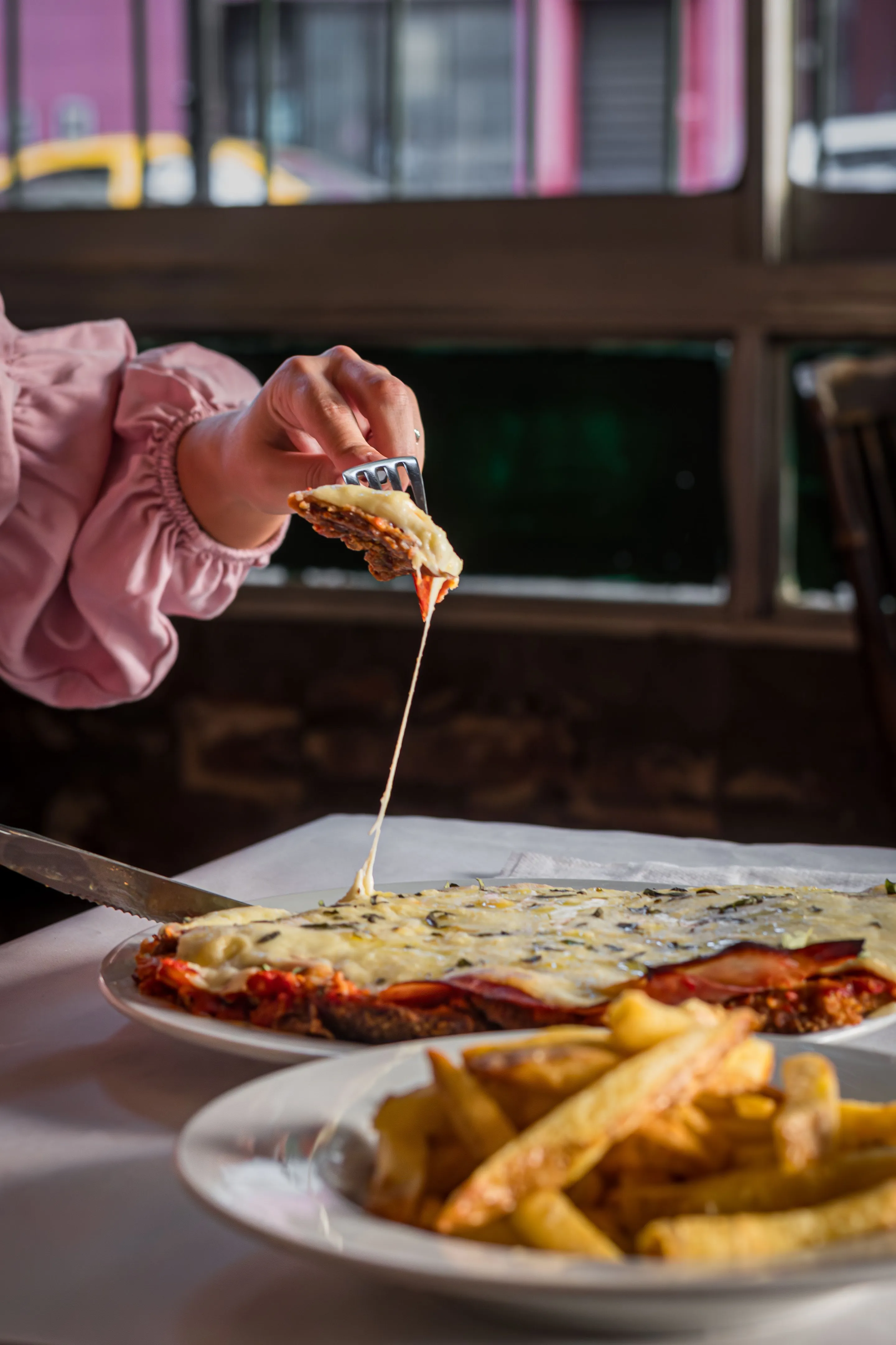 A milanesa topped with melted cheese being served at a Buenos Aires table