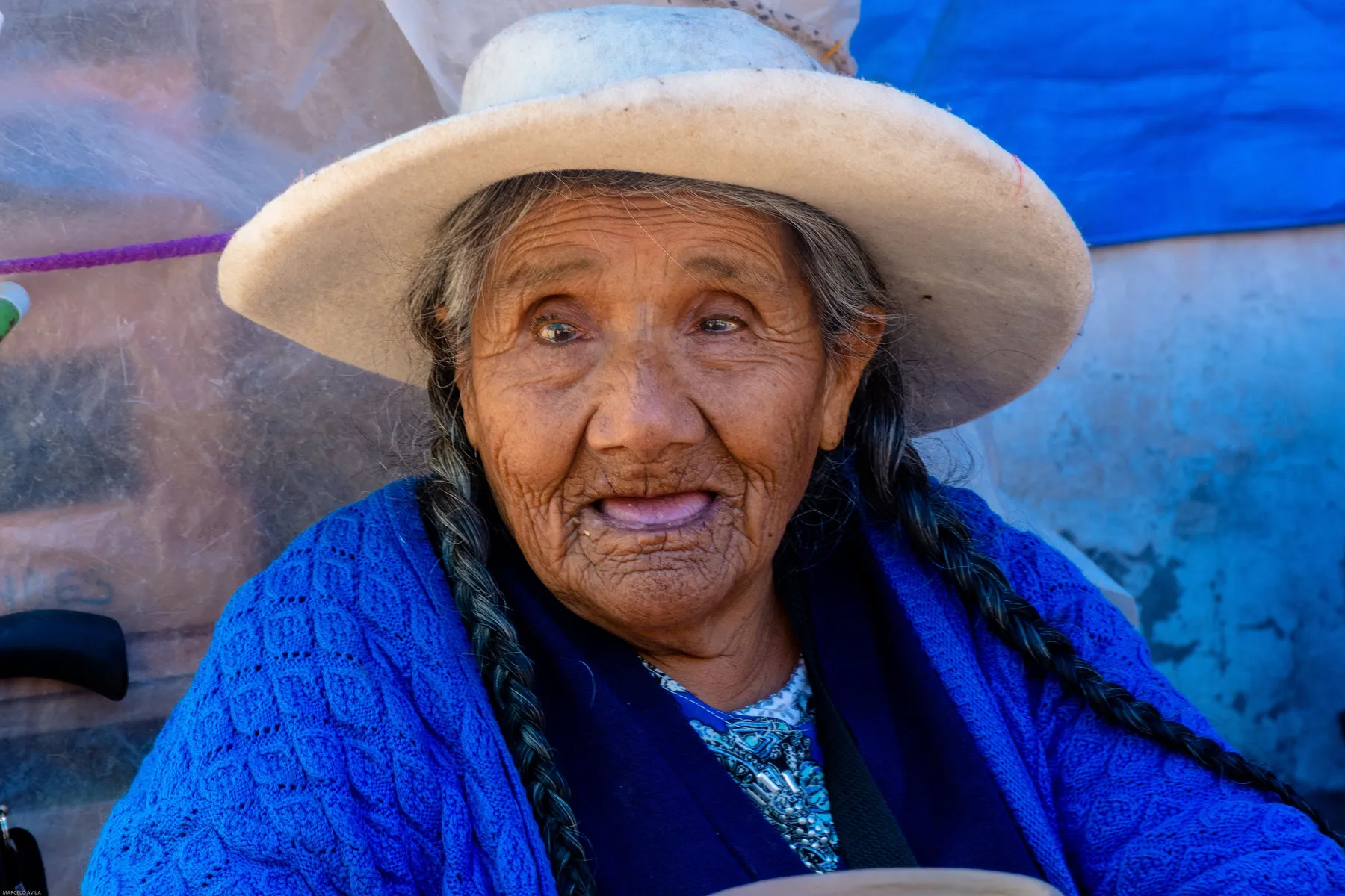 Portrait of a woman in a white hat and patterned blue sweater in Humahuaca