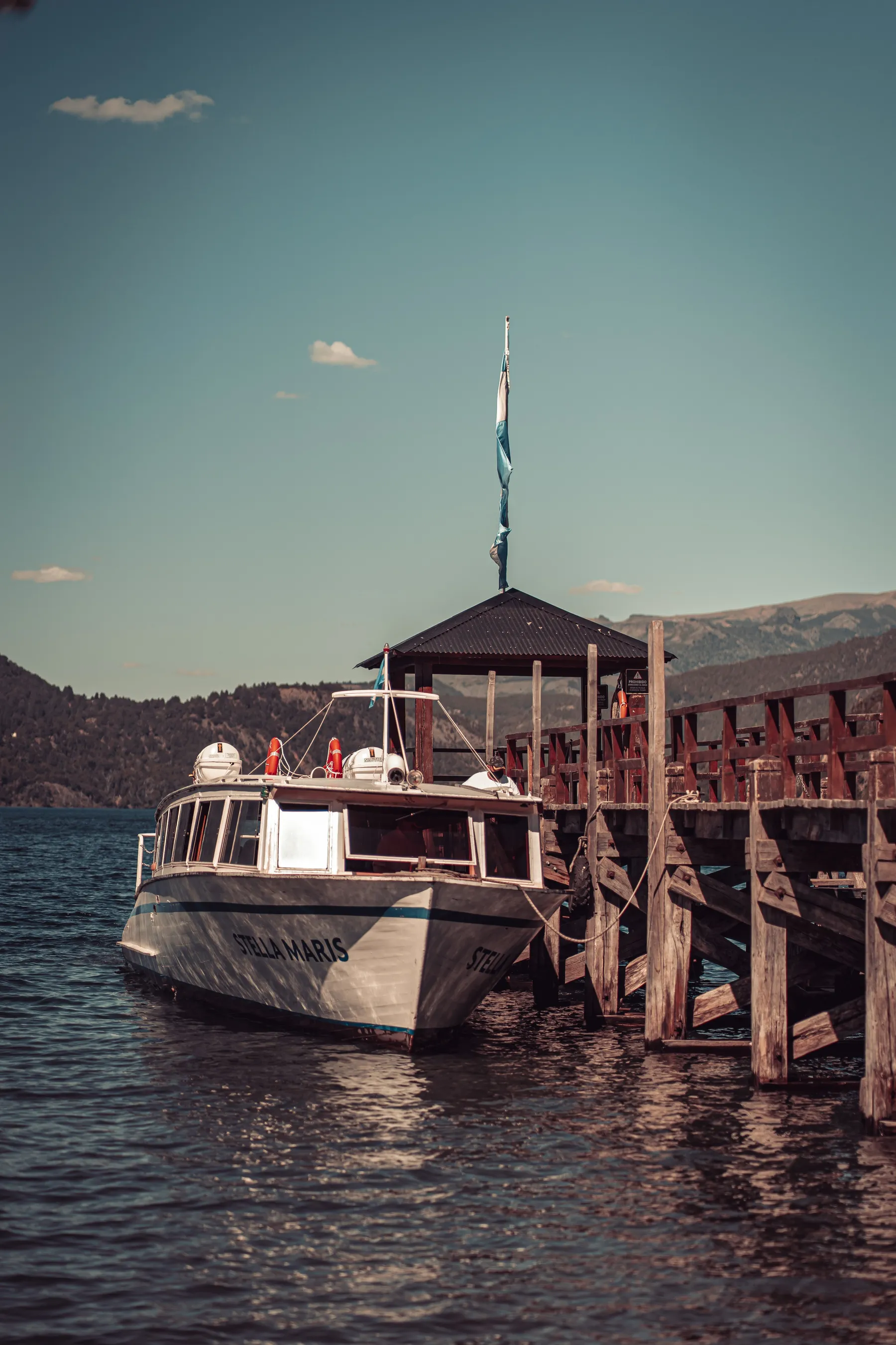 Boat at the Quila Quina pier with wooded shores and mountains beyond