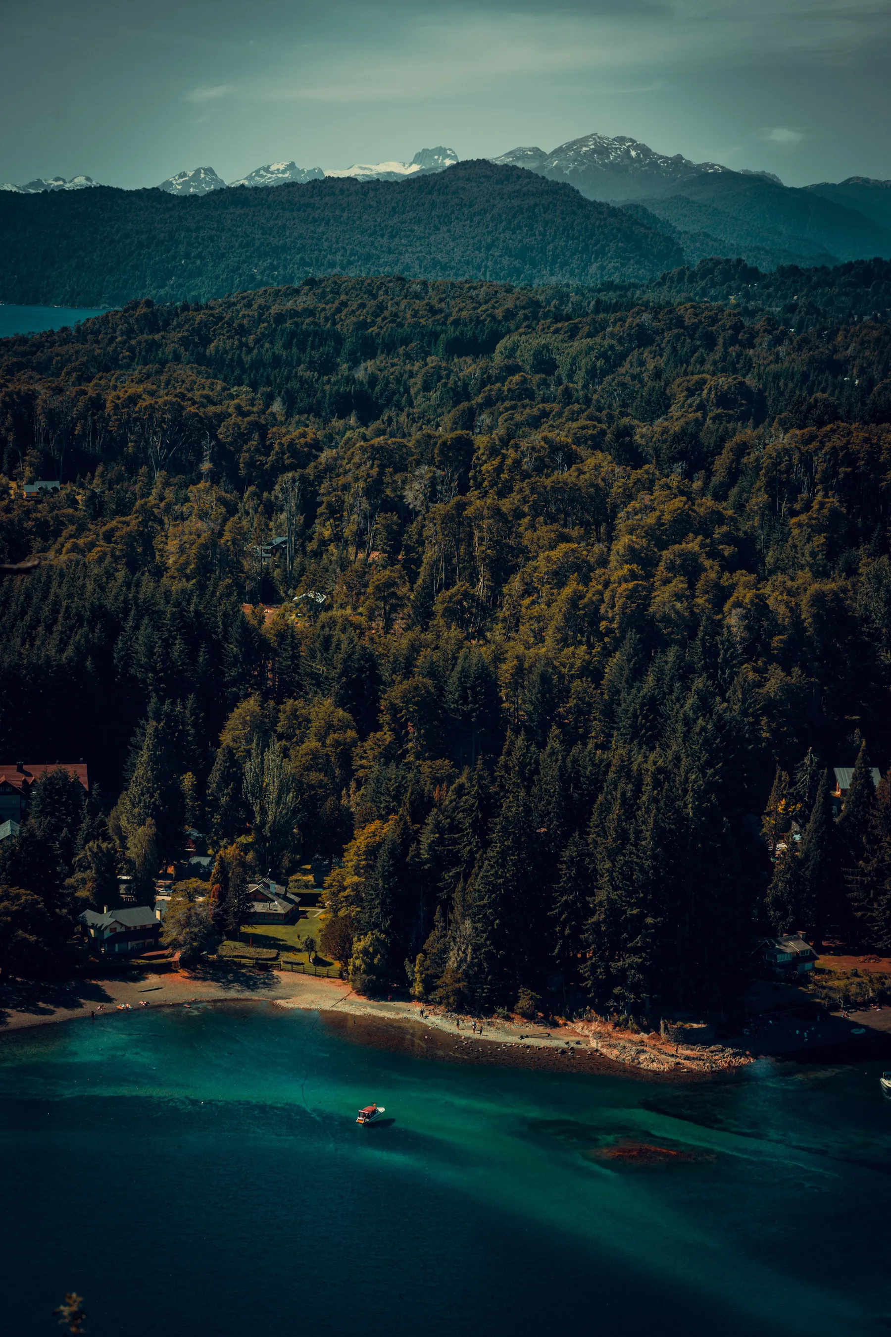 Forested slopes and blue lake water beneath the mountains around Bariloche