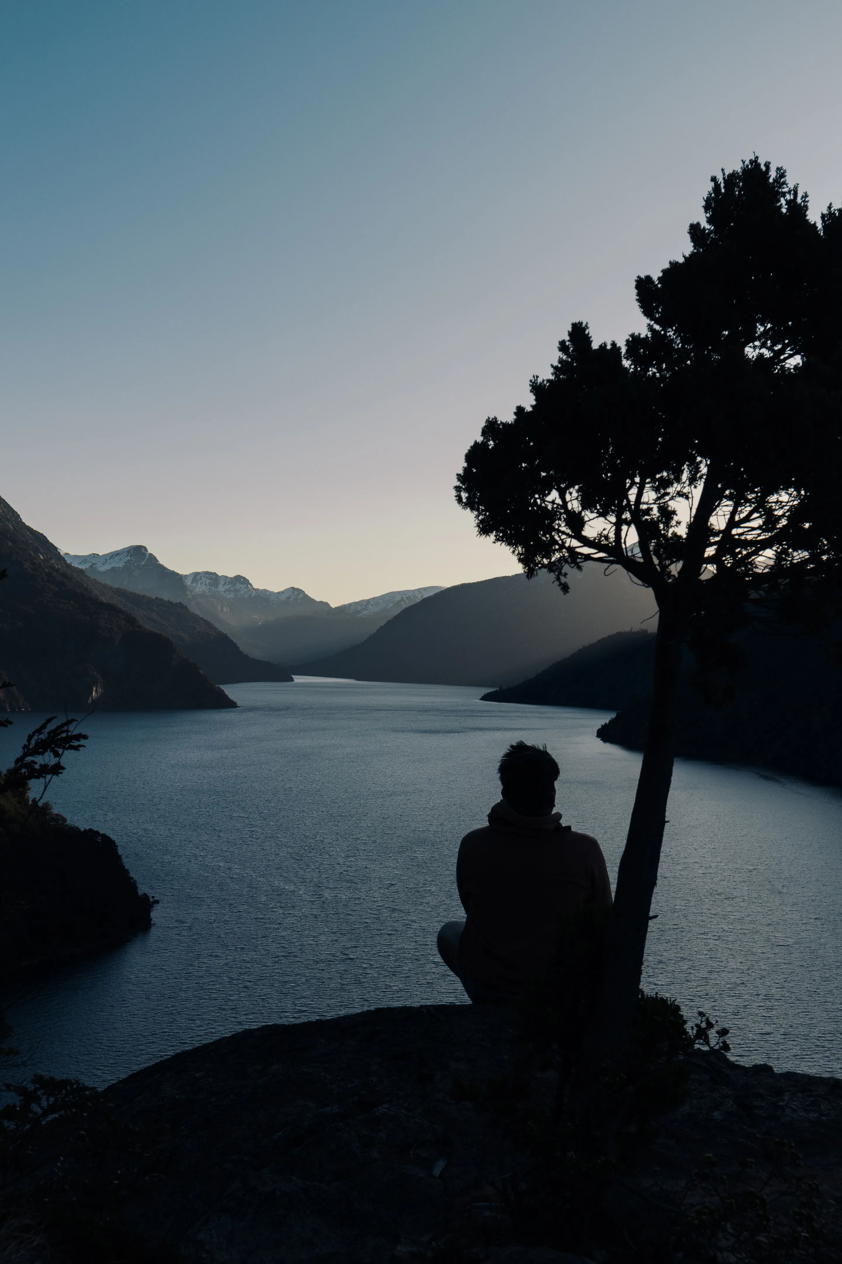 A person looking across a Patagonian lake beneath the evening mountains.