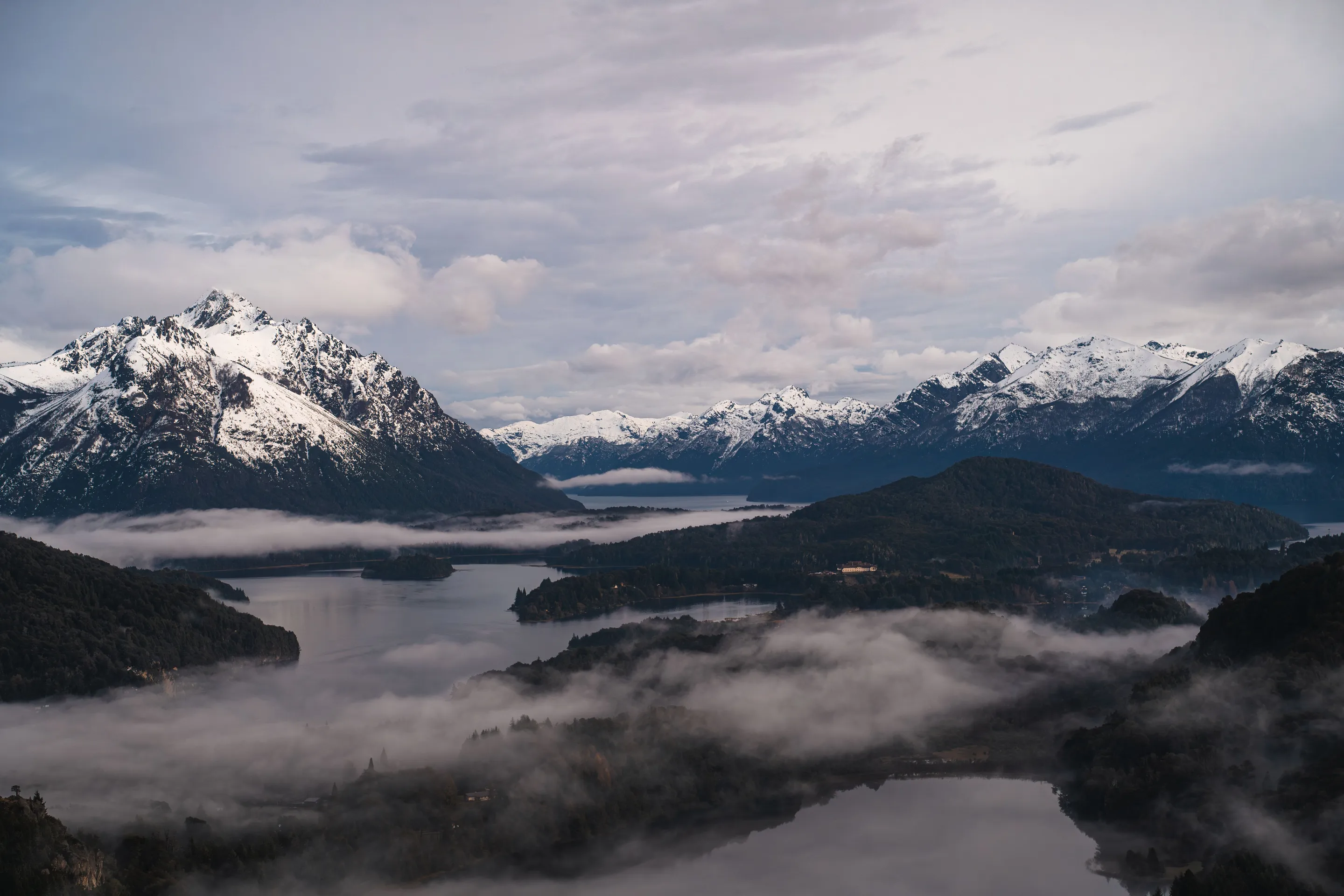 Snowy mountains and mist over water in Bariloche.