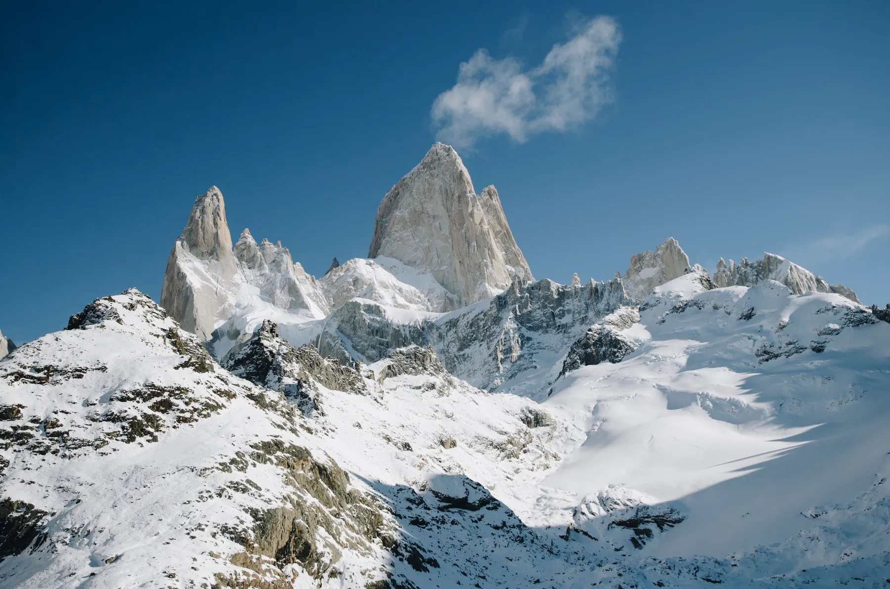Snow-covered Fitz Roy peaks beneath a clear blue sky