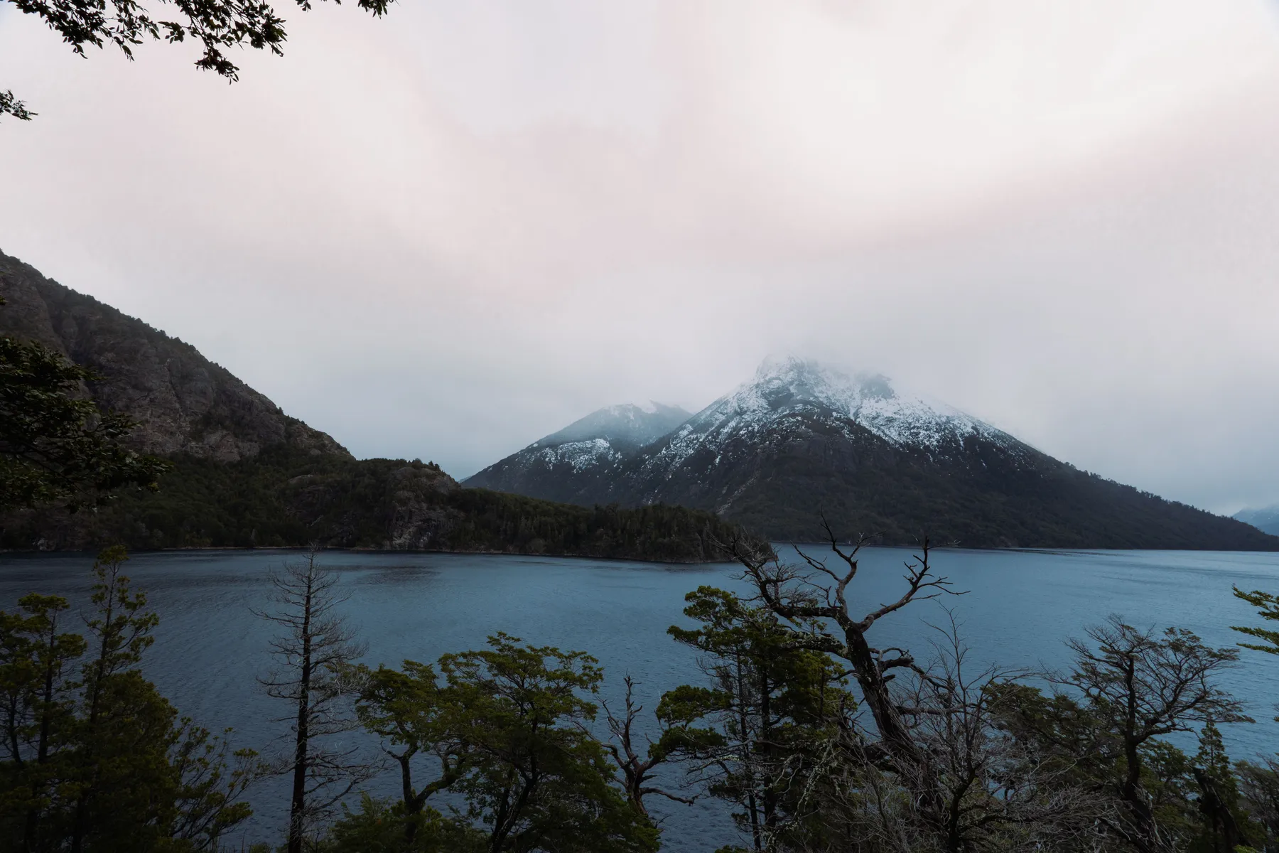 Snow-covered mountain slopes above a still lake near Bariloche