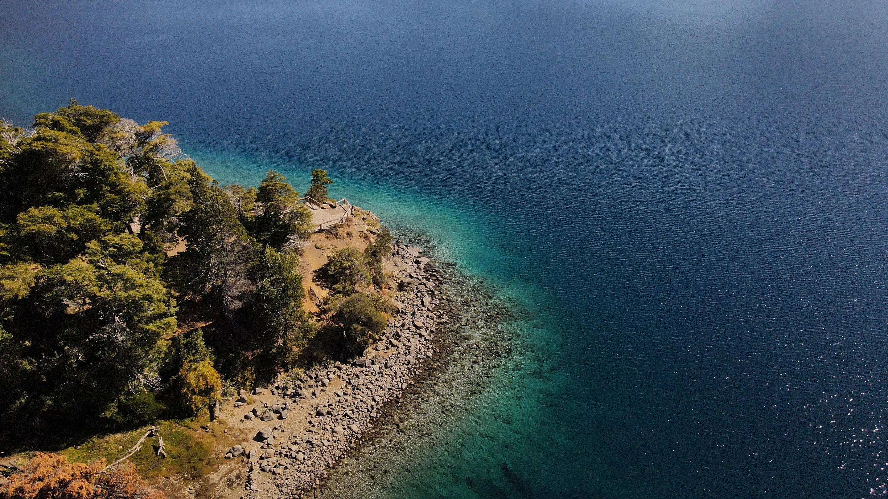 Clear turquoise shallows and wooded shoreline at Lake Traful