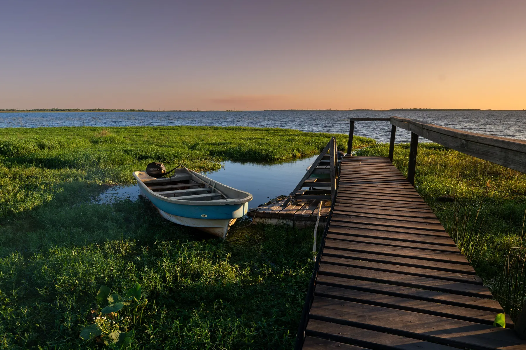 A boat and dock silhouetted against sunset light on the water