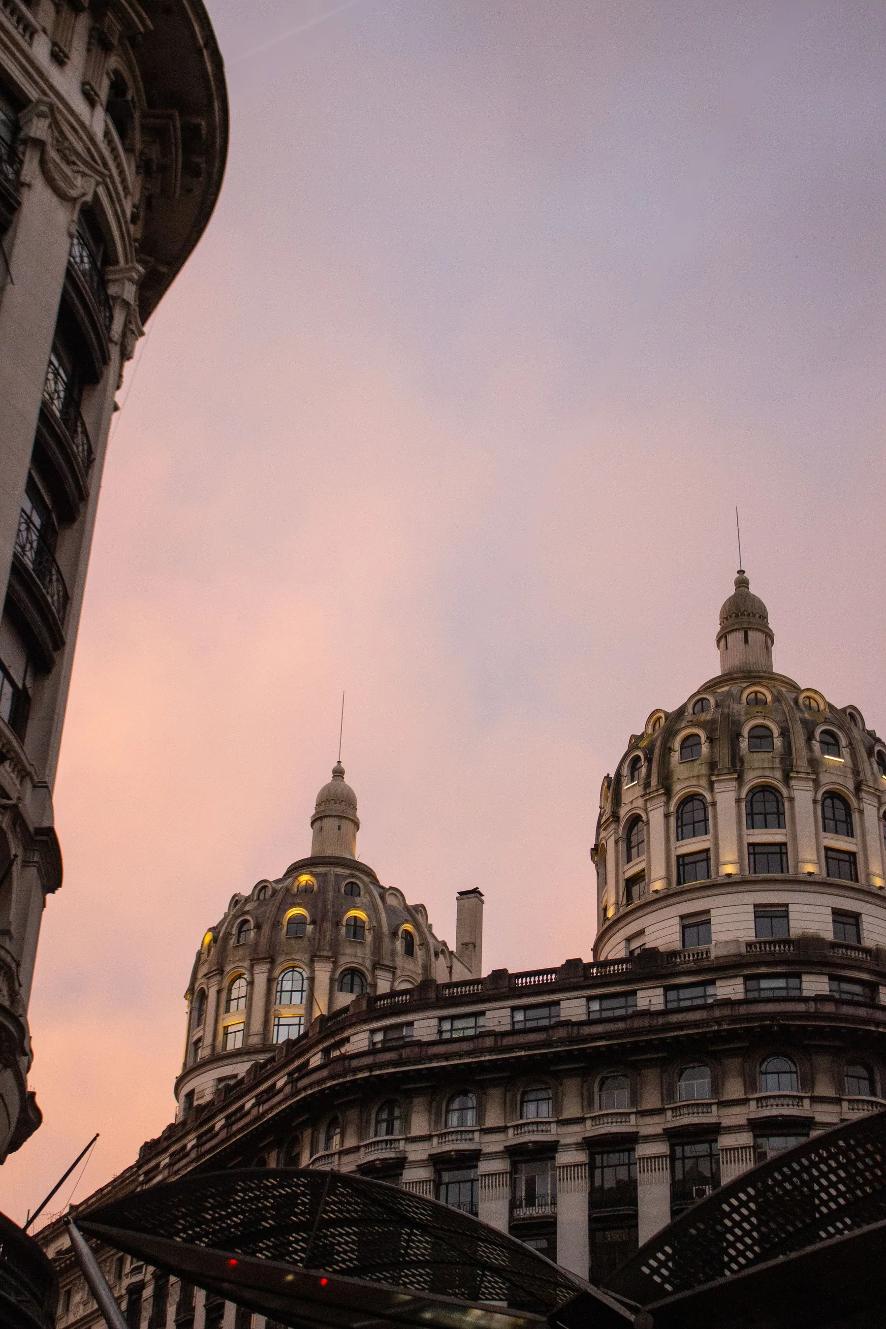 Ornate domes above a Buenos Aires street beneath a pink evening sky