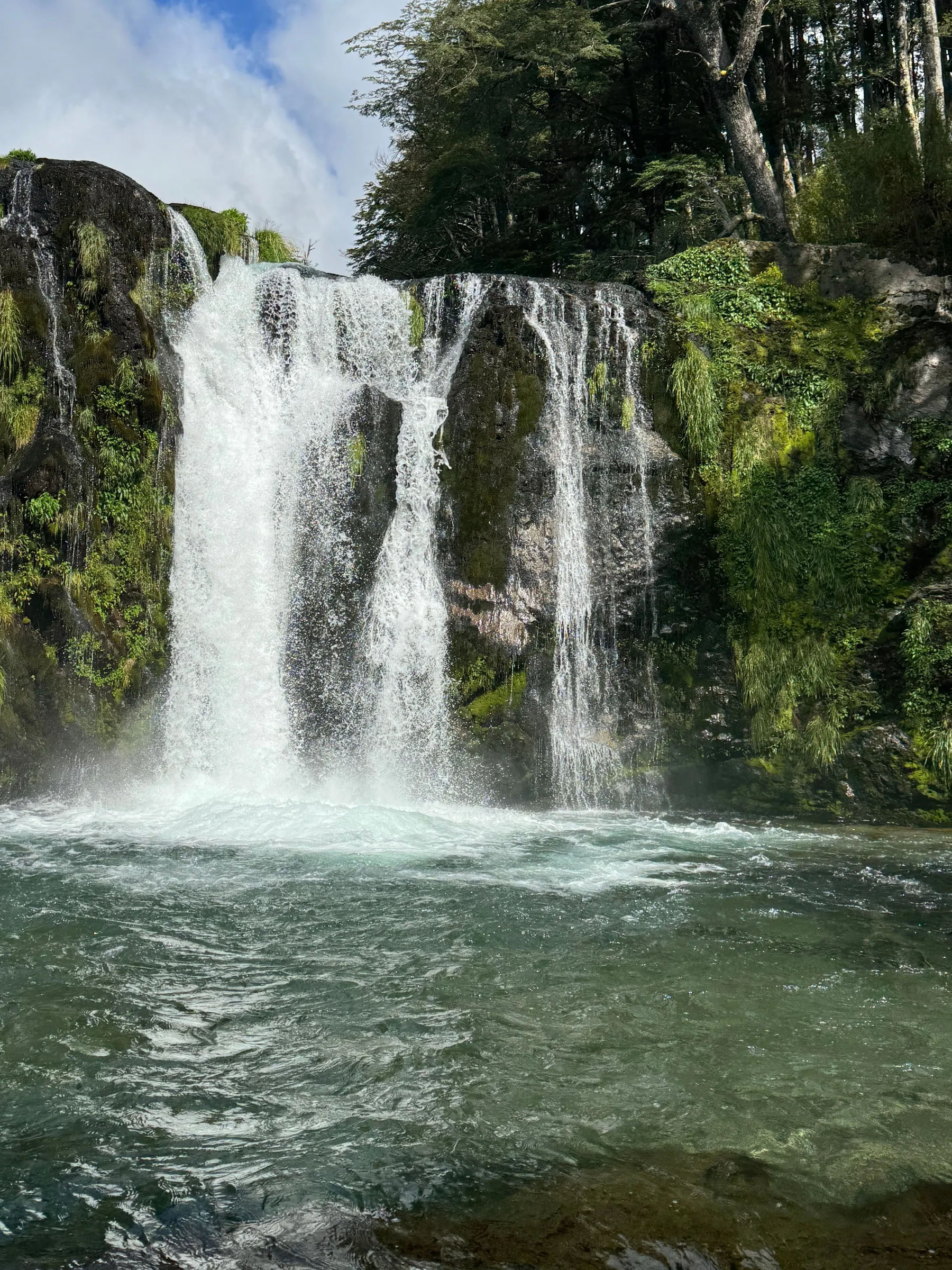 Waterfall cascading through a green forest near Villa La Angostura