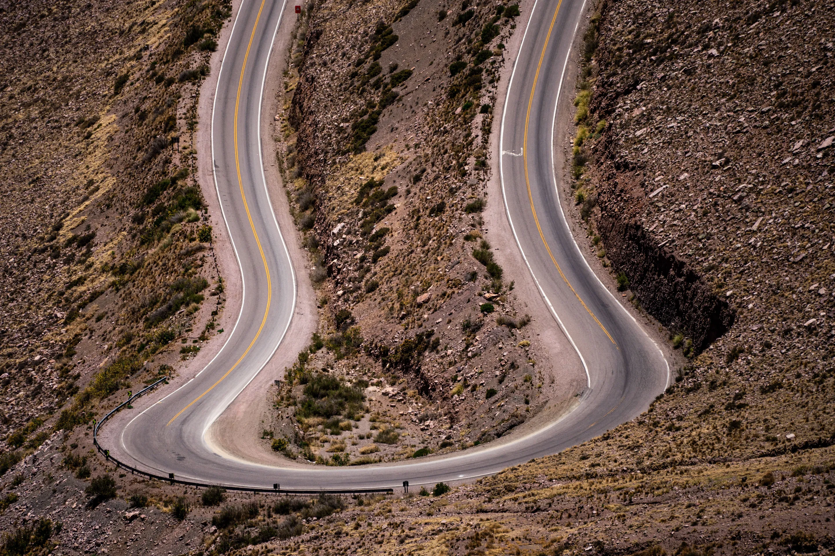 An aerial view of a winding road through rugged mountain country.