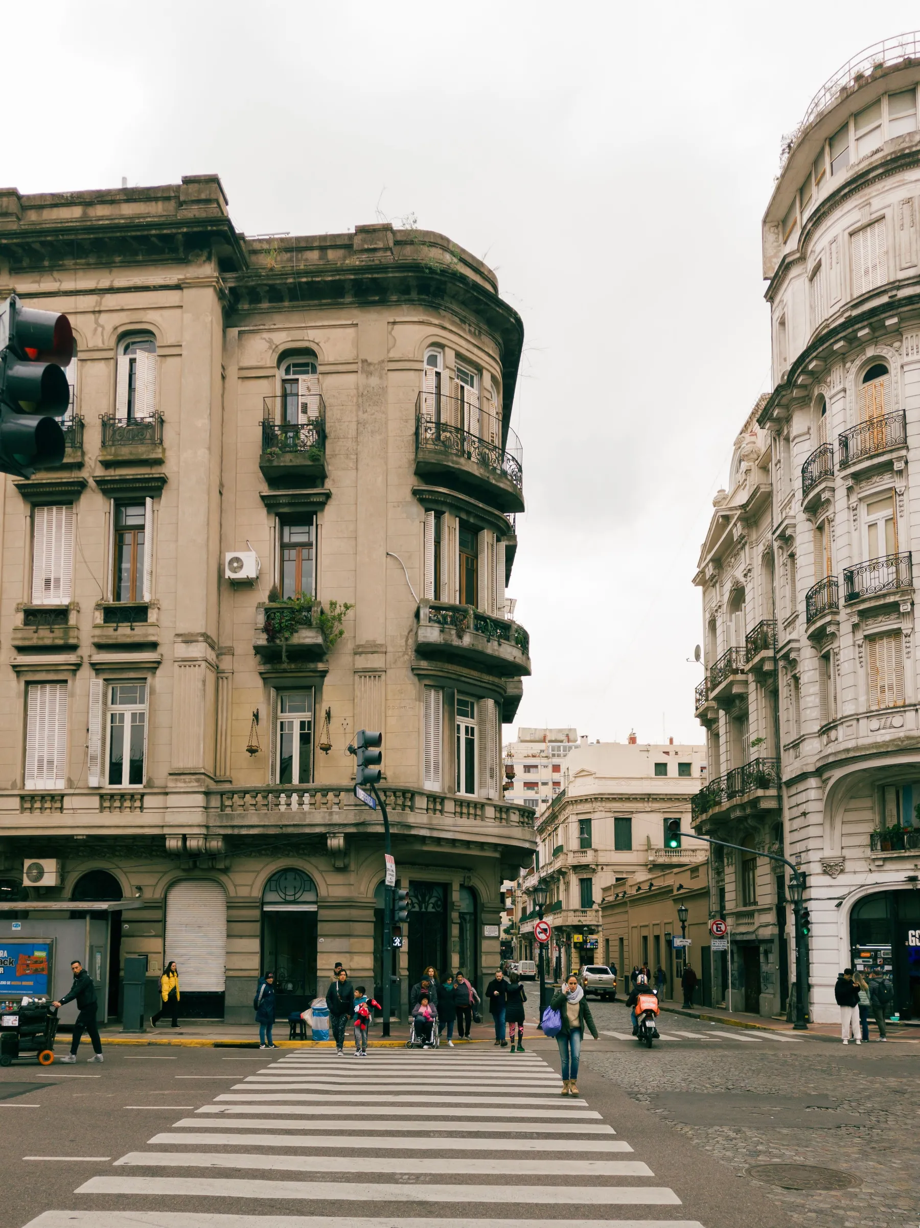 Pedestrians crossing a street beneath a classical San Telmo corner building