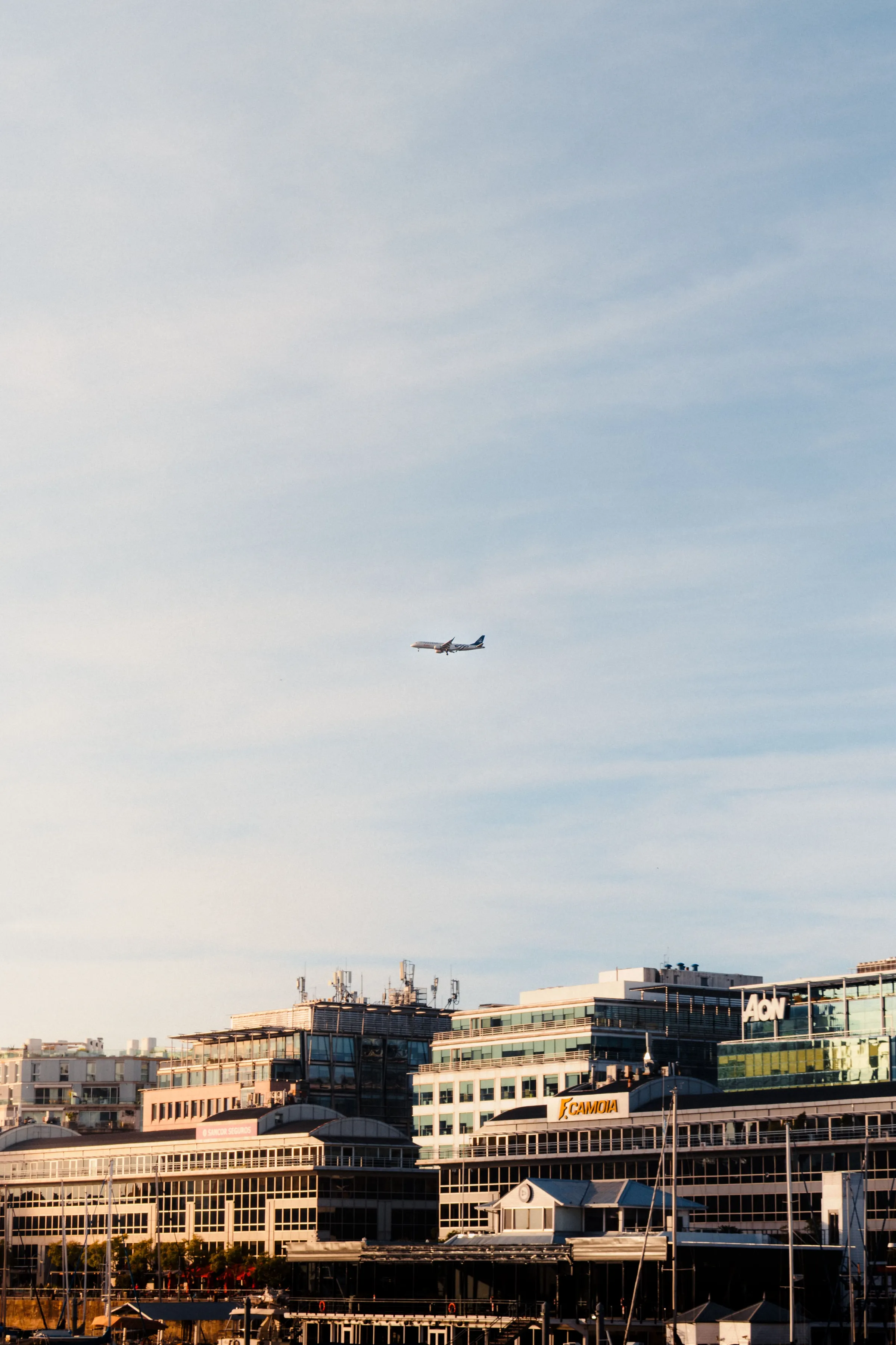 An aircraft above the Puerto Madero skyline in the evening light.
