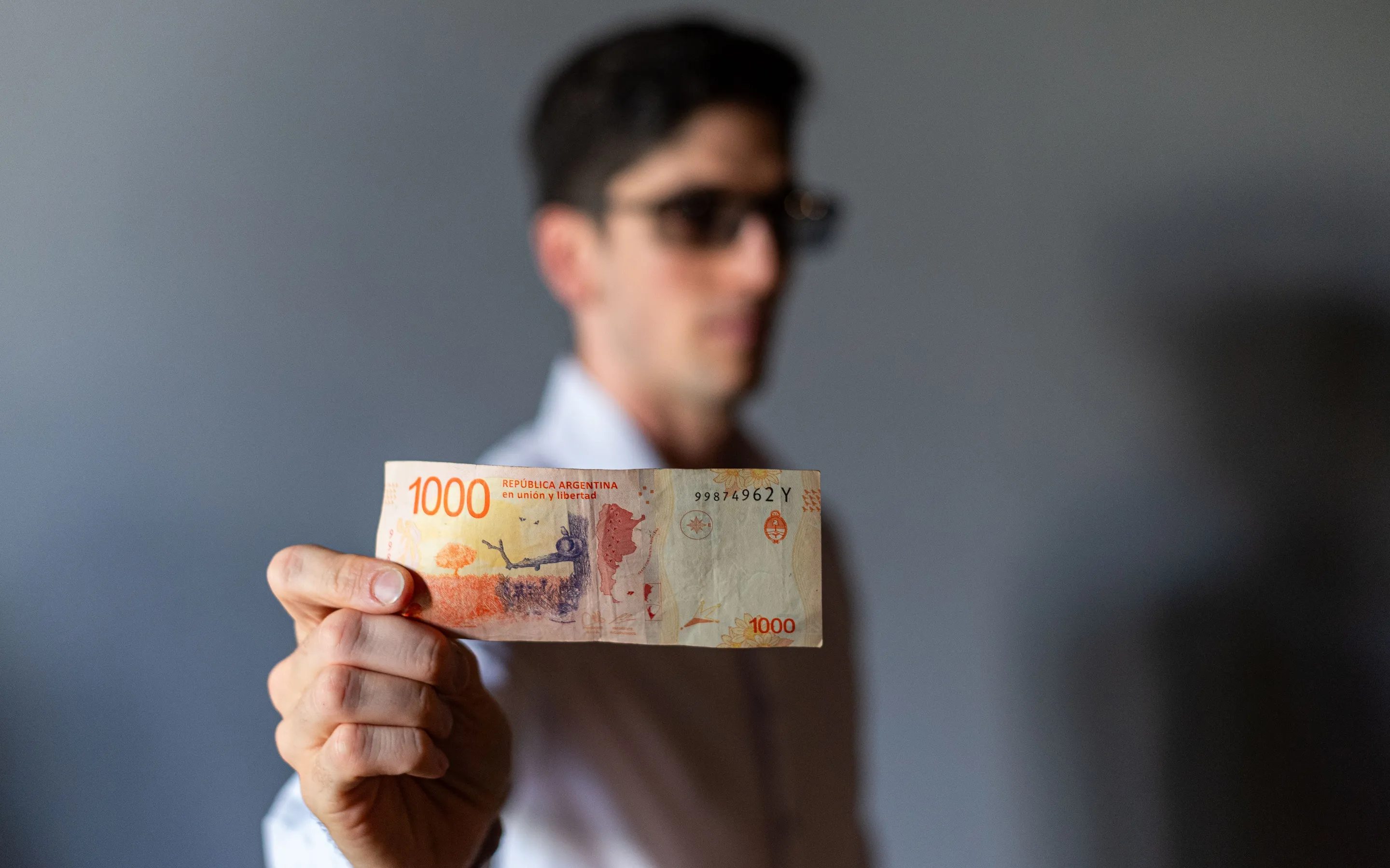 A close view of an Argentine peso banknote held in a hand.