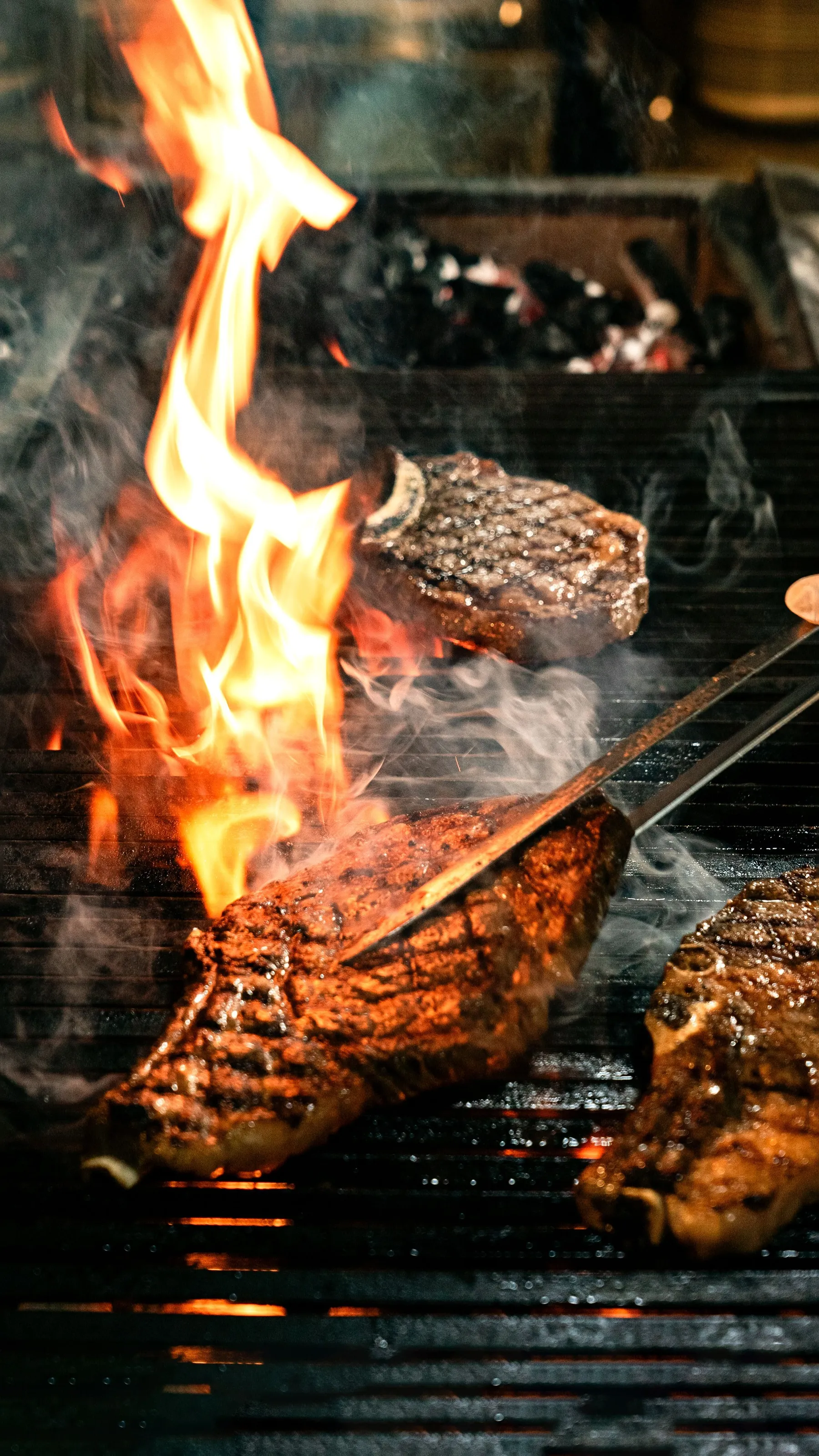 Steak searing on a barbecue grill amid open flames