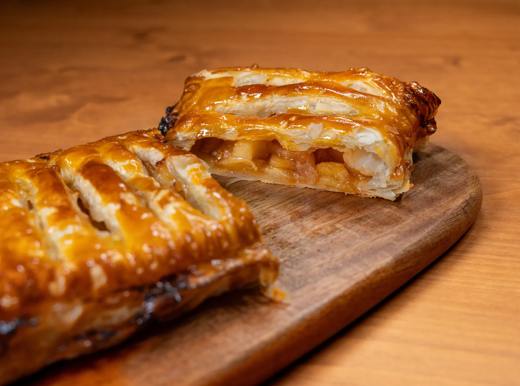 Close-up of golden apple pastry cut open on a wooden board