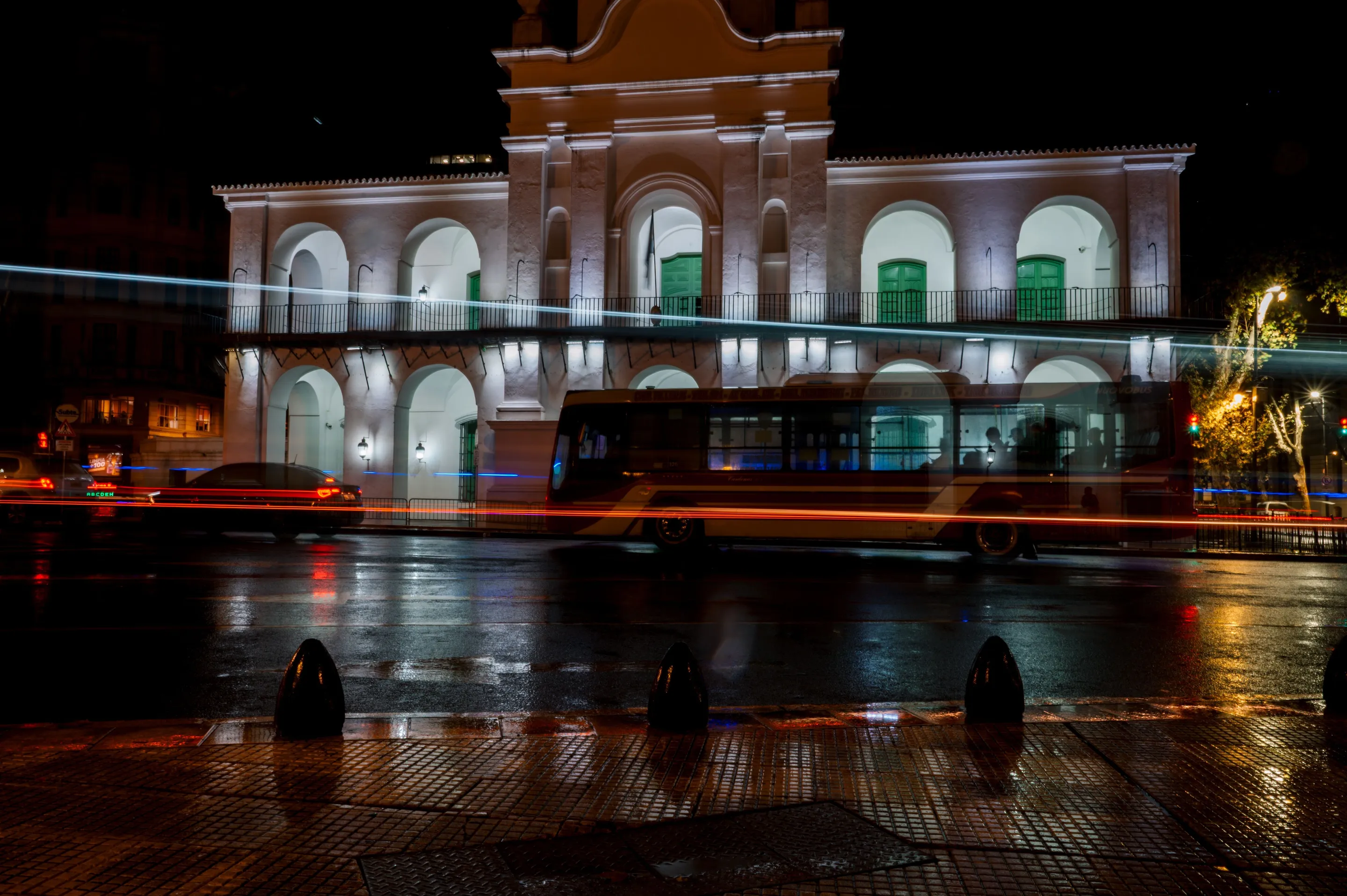 Illuminated Casa Rosada and light trails reflected on a wet street at night