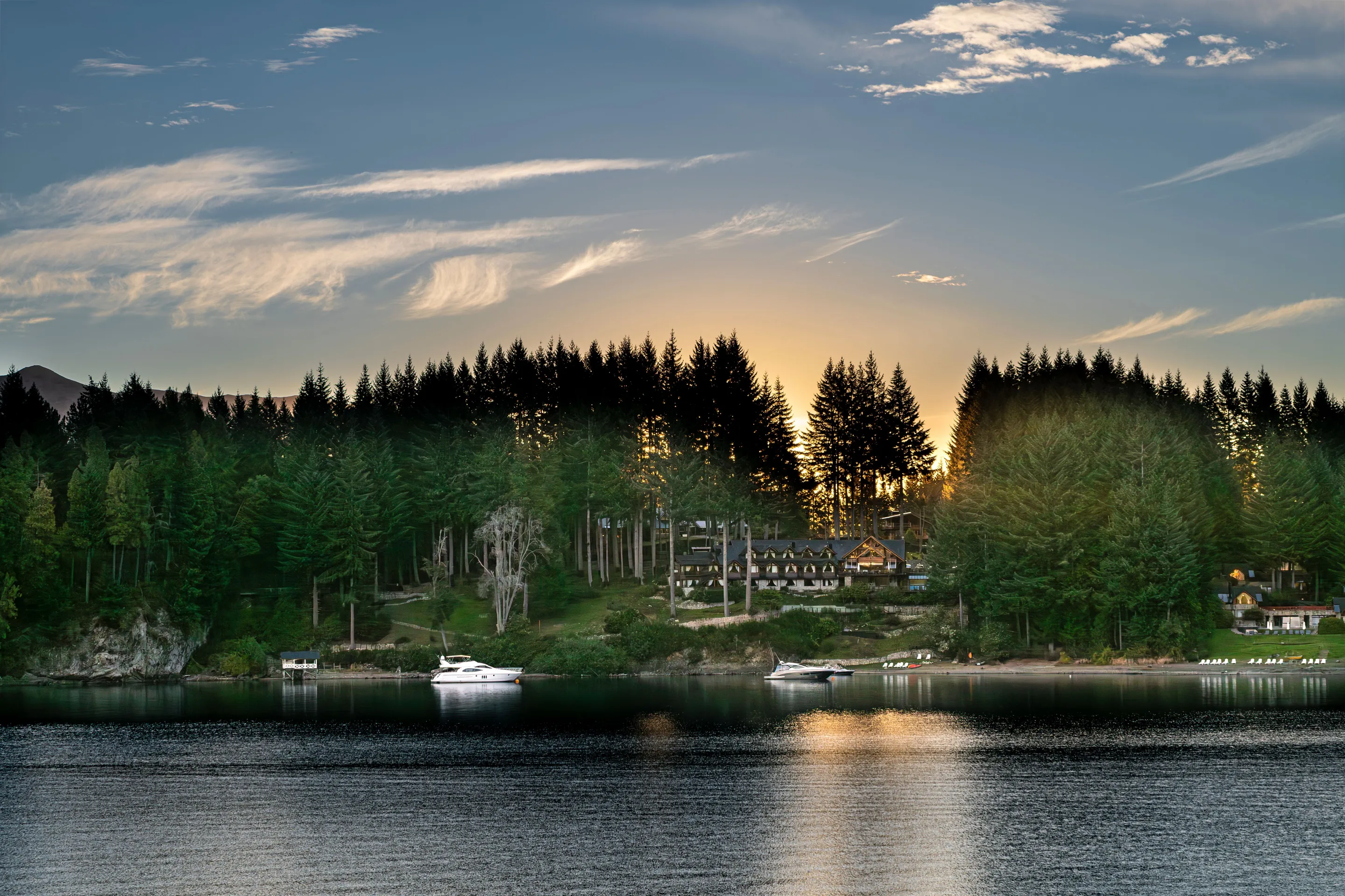 Evening colour above boats and forest at Villa La Angostura
