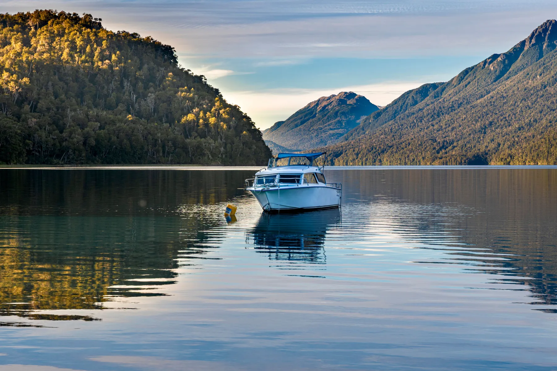 A small boat framed by forested mountains near Villa La Angostura