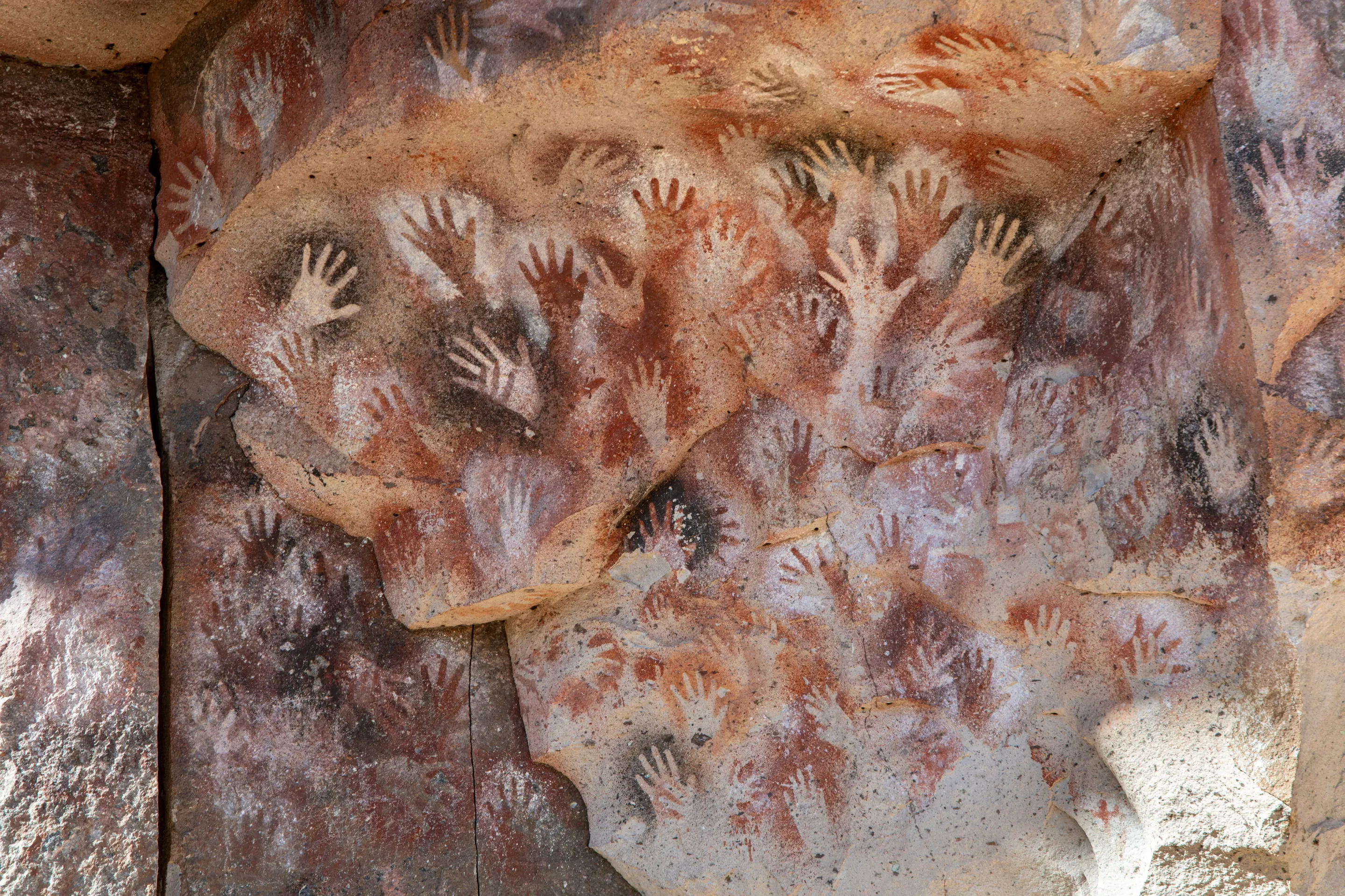 Layers of painted hands on the shelter wall