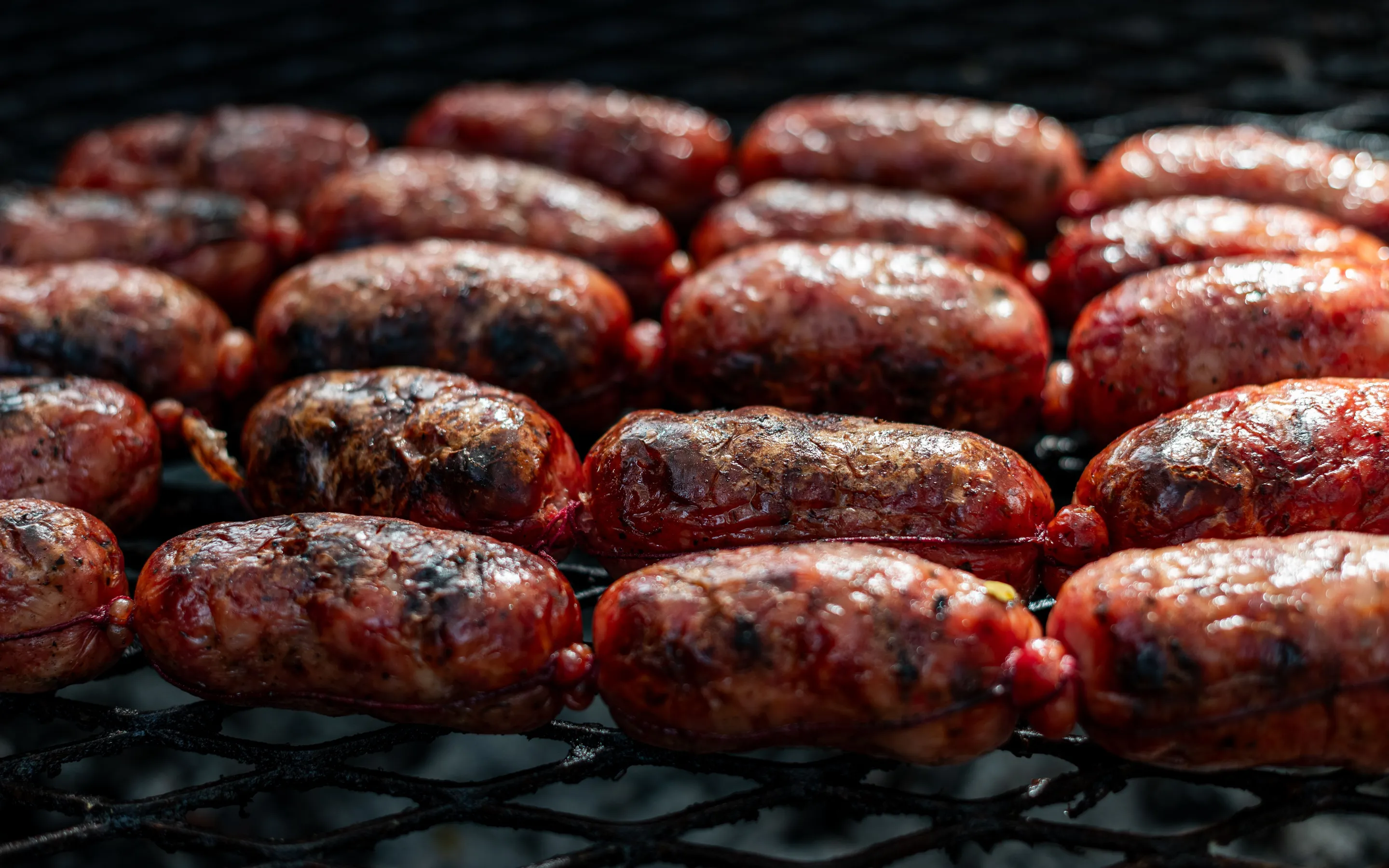 A close view of chorizo cooking on an outdoor grill.