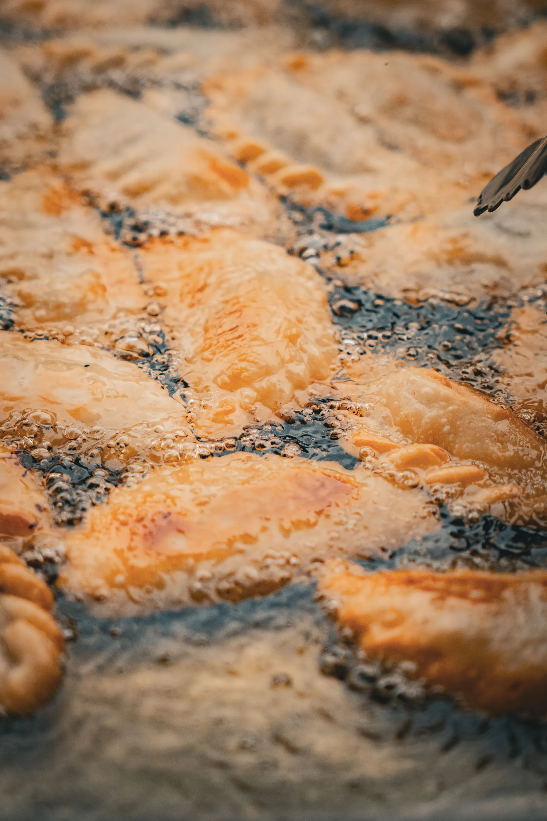 Empanadas browning in bubbling hot oil