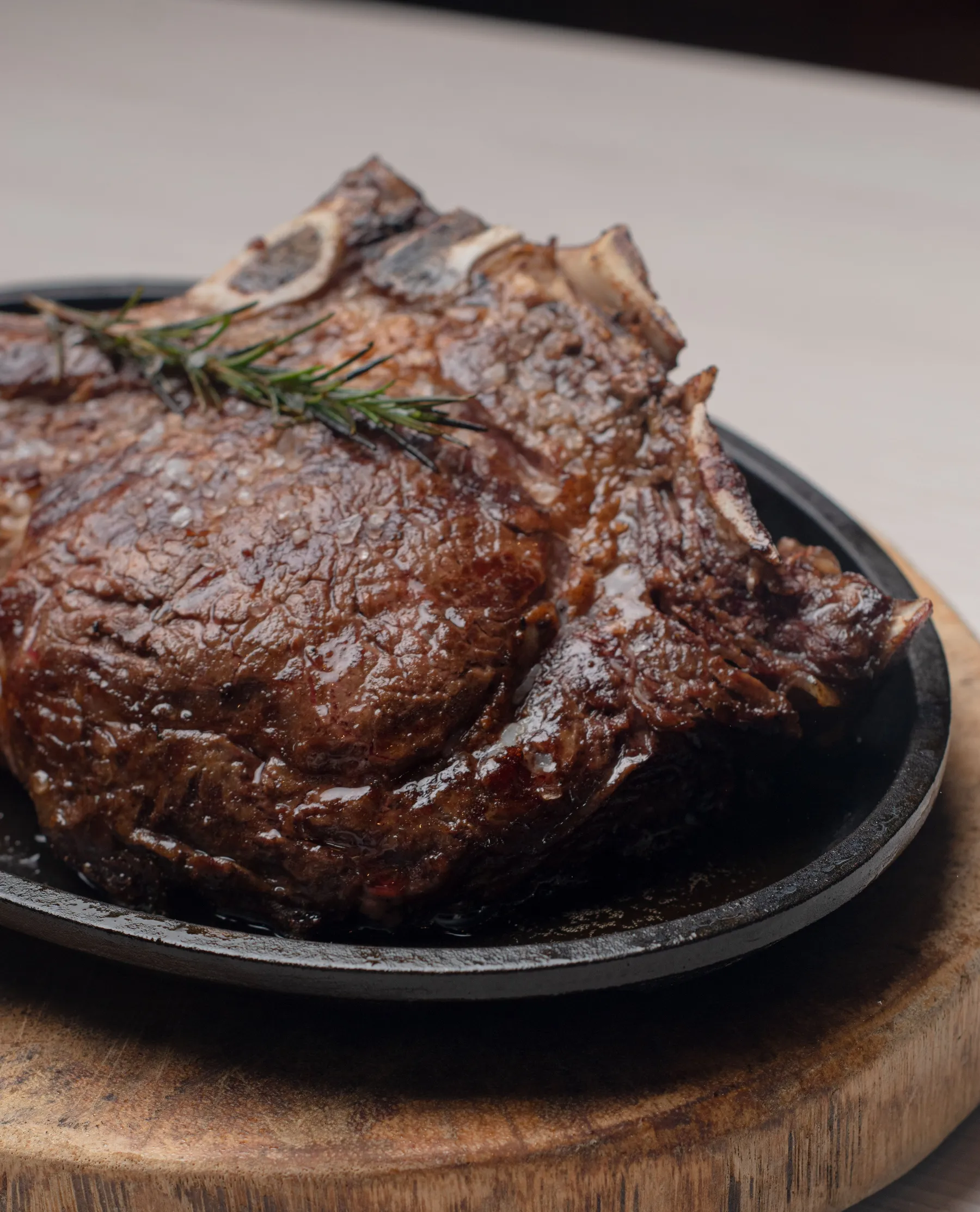 A browned steak with rosemary on a dark plate