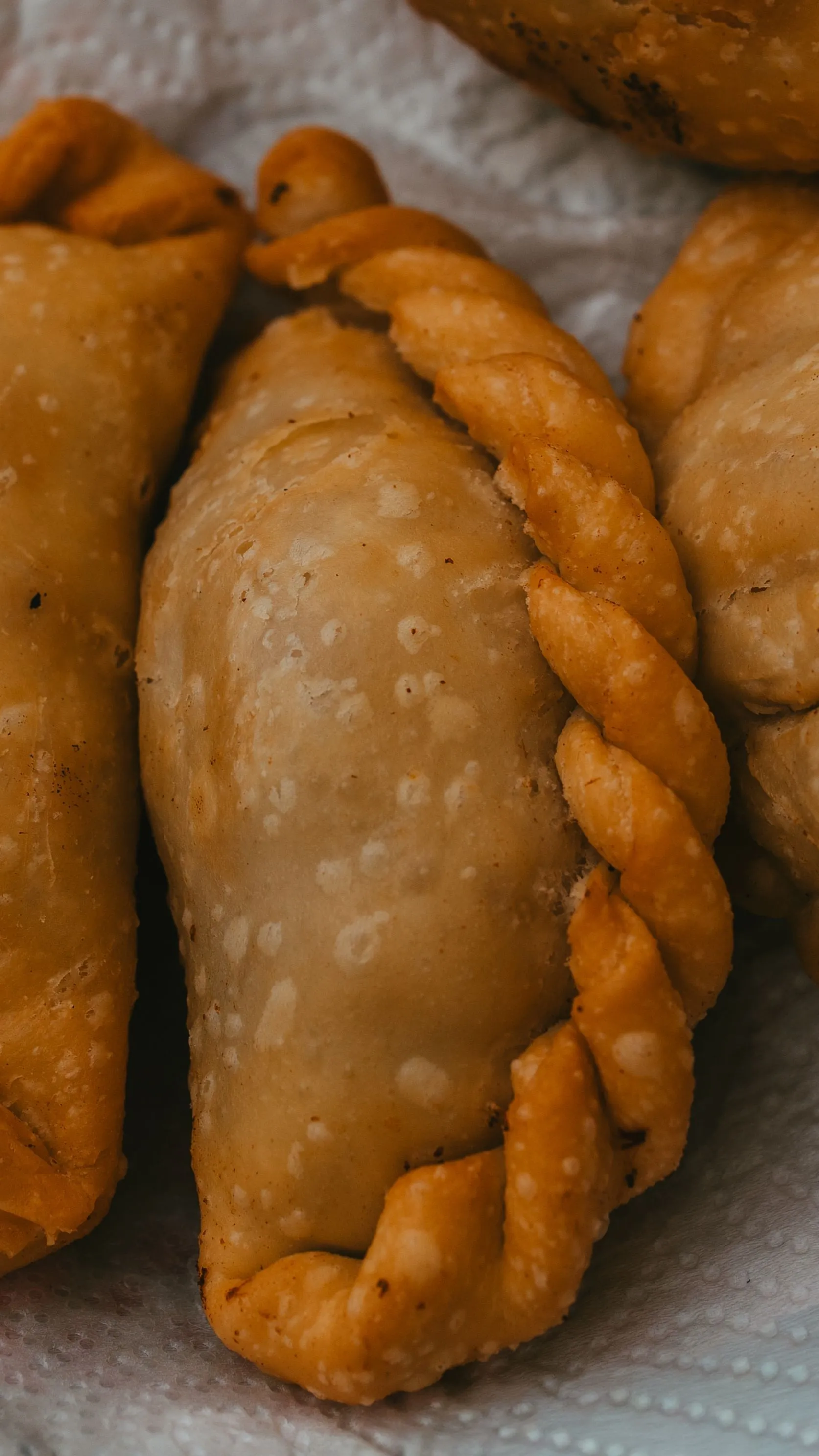 A close view of golden Argentine empanadas and their crimped pastry