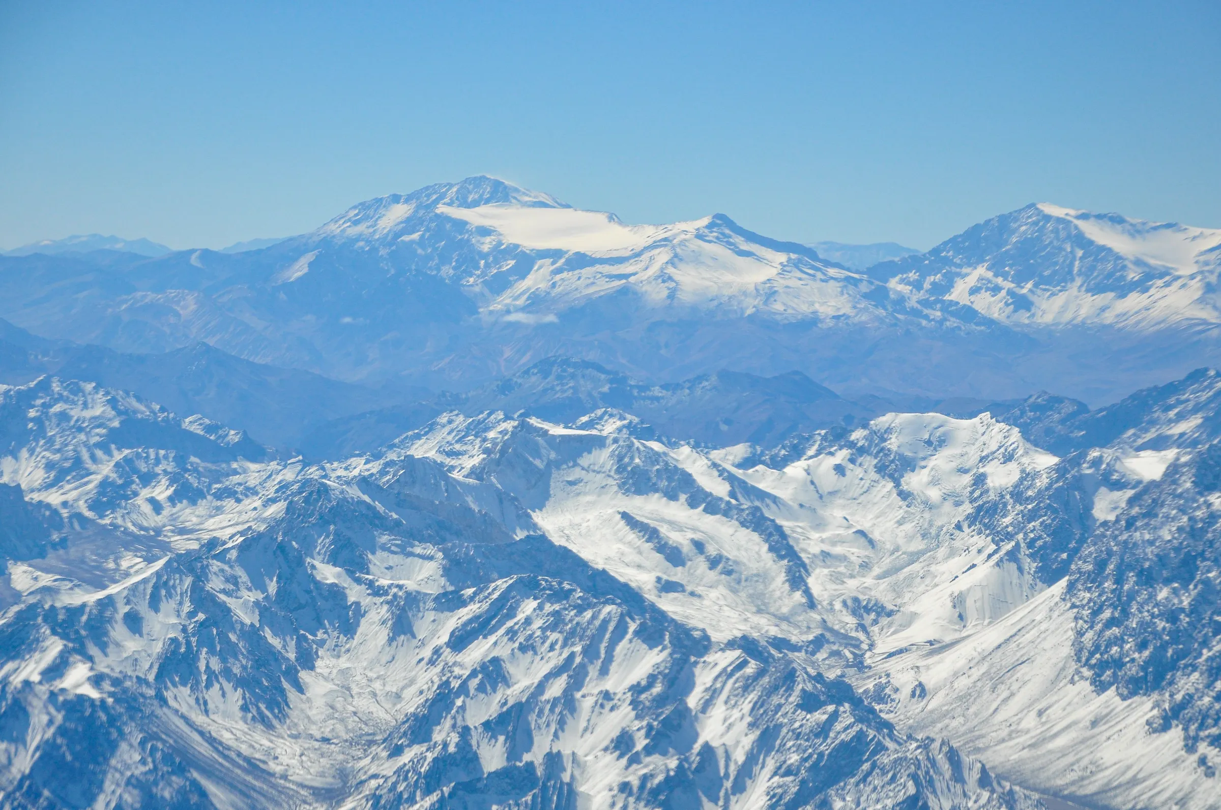 Snow-capped peaks in Mendoza's Andes beneath a blue sky.