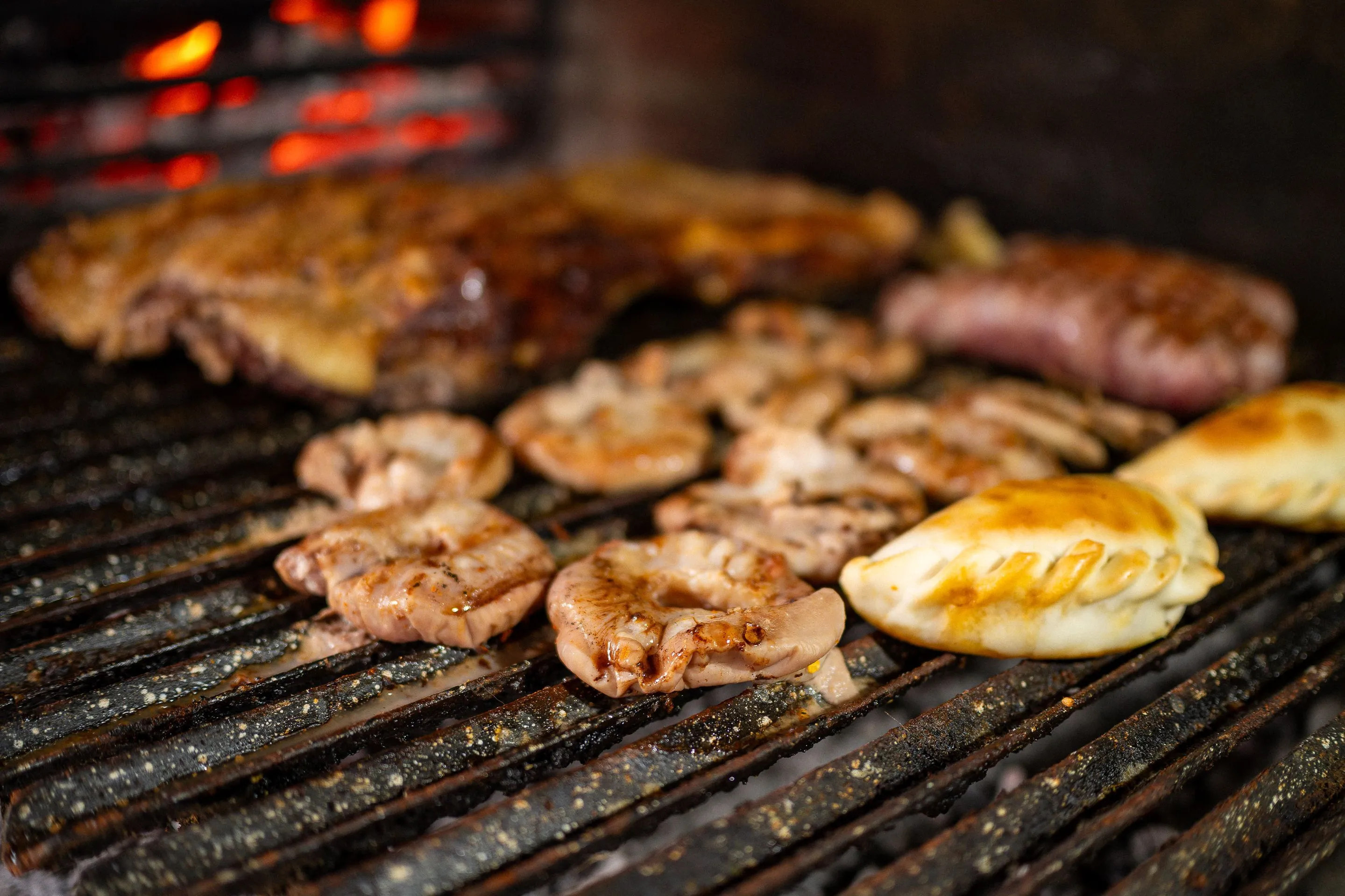 Meat and empanadas cooking over a hot Argentine grill.