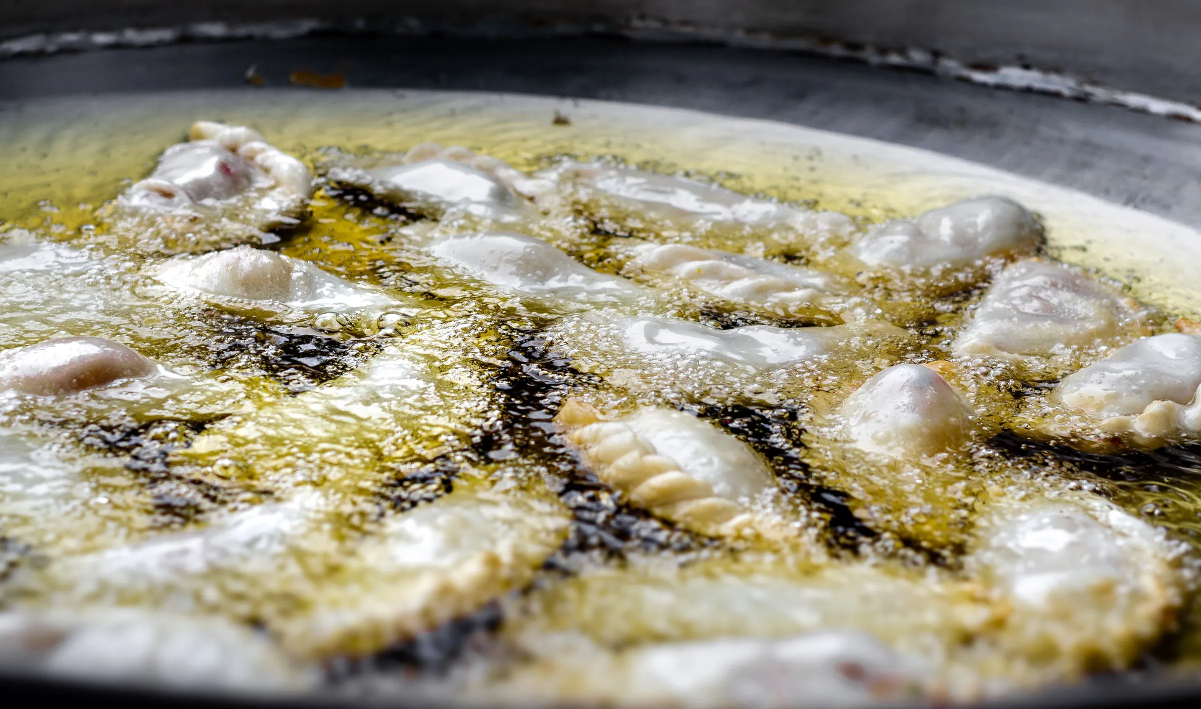 Empanadas turning golden while frying in hot oil.
