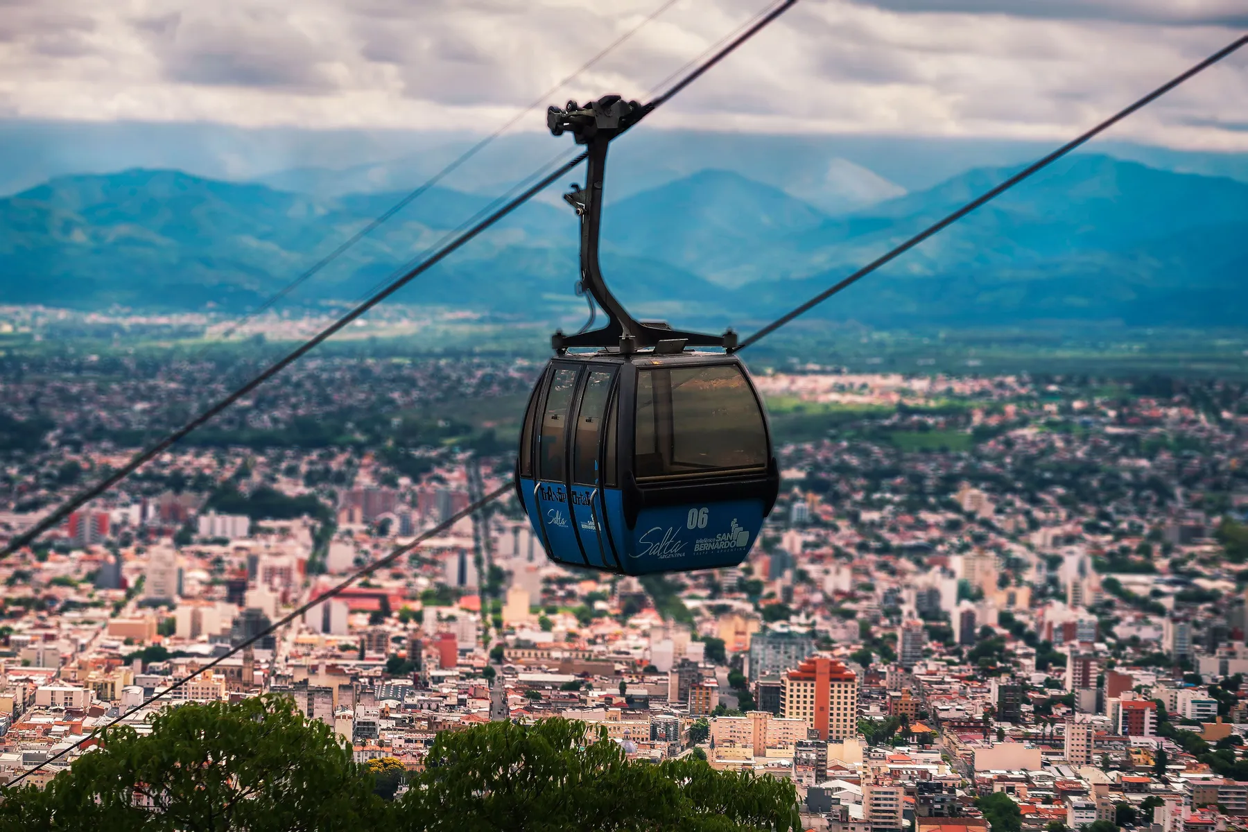A cable car above trees and rooftops in Salta