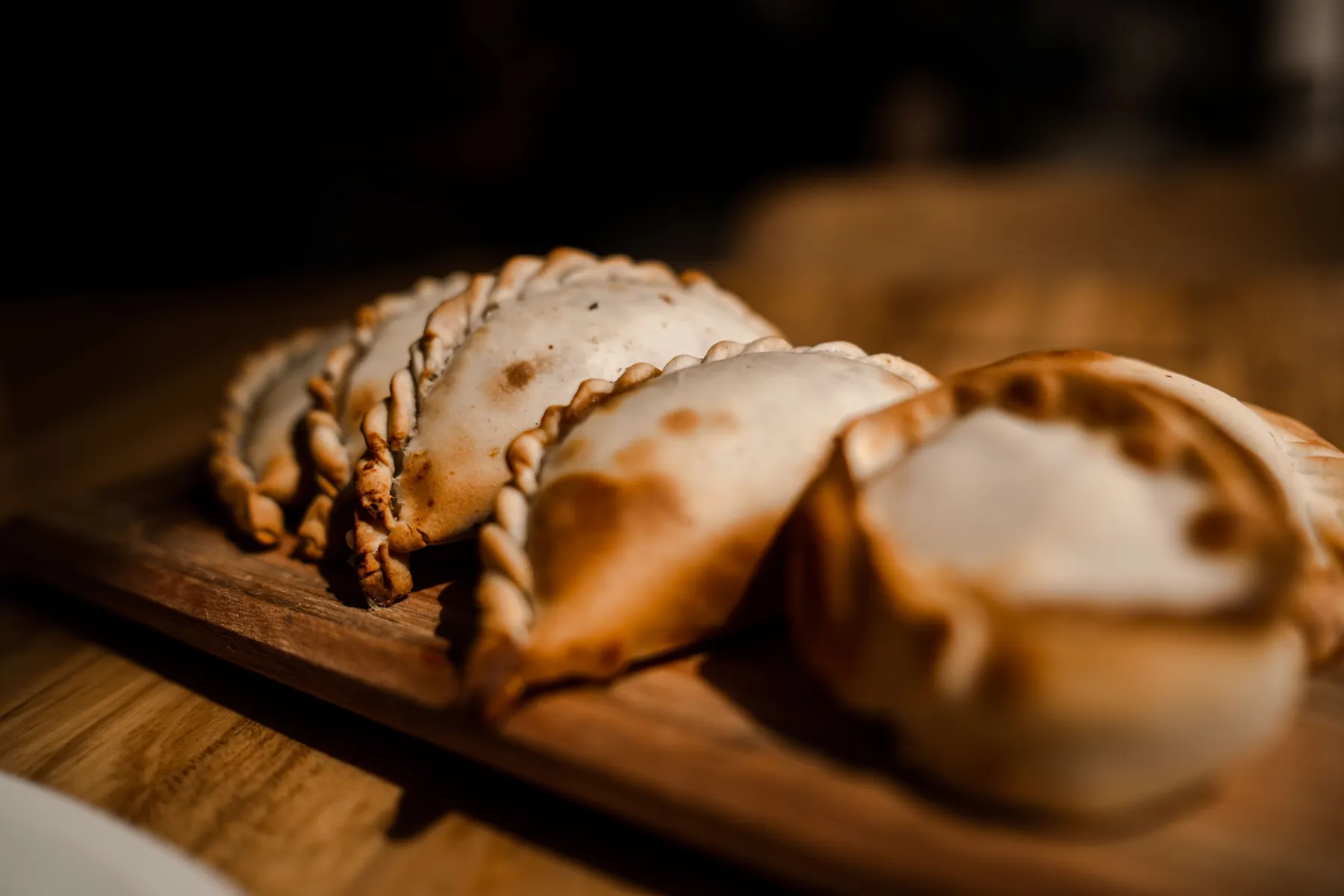 Close-up of golden empanadas on a wooden surface