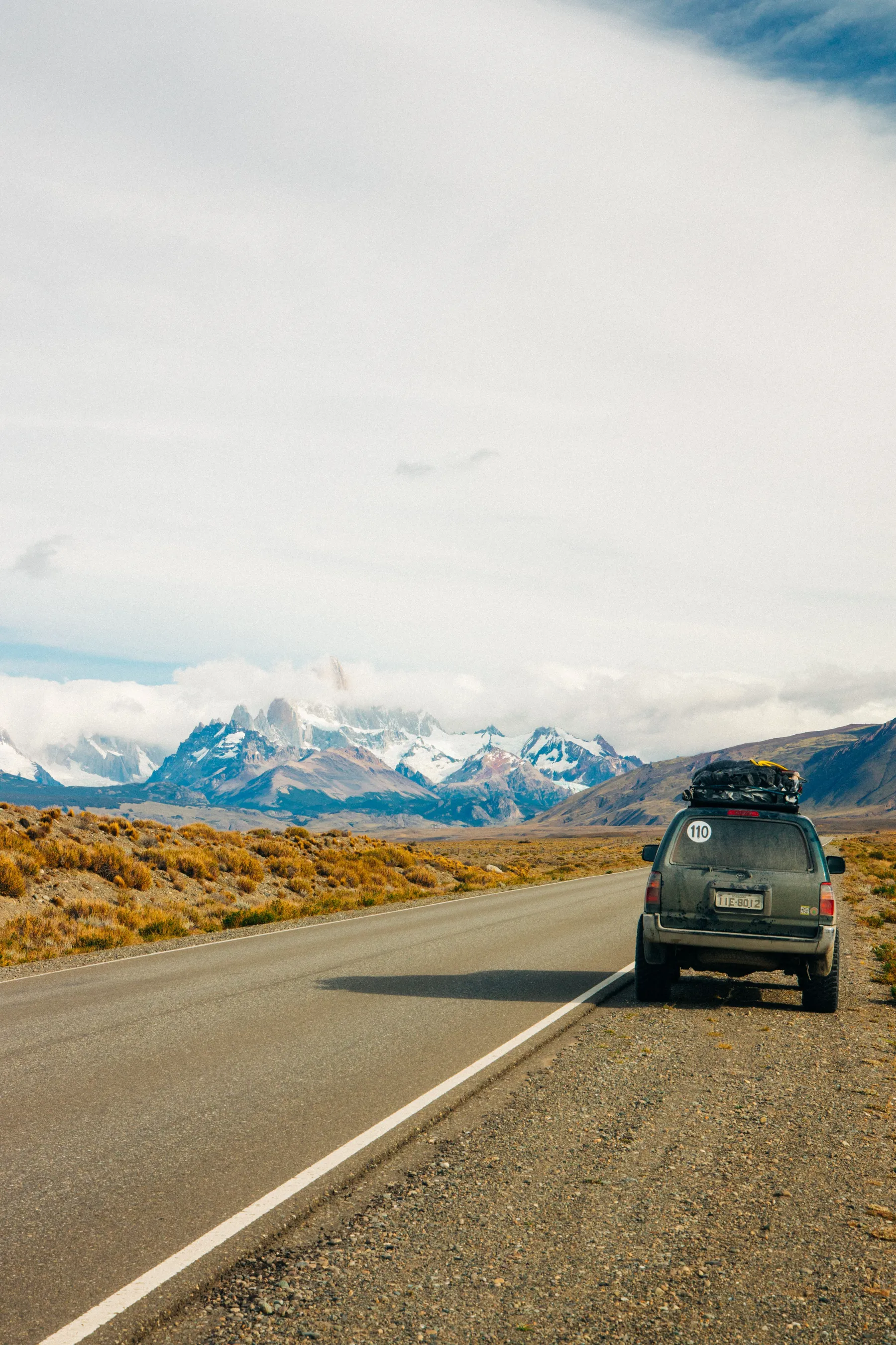 A car on the road beneath mountain scenery near El Chaltén.