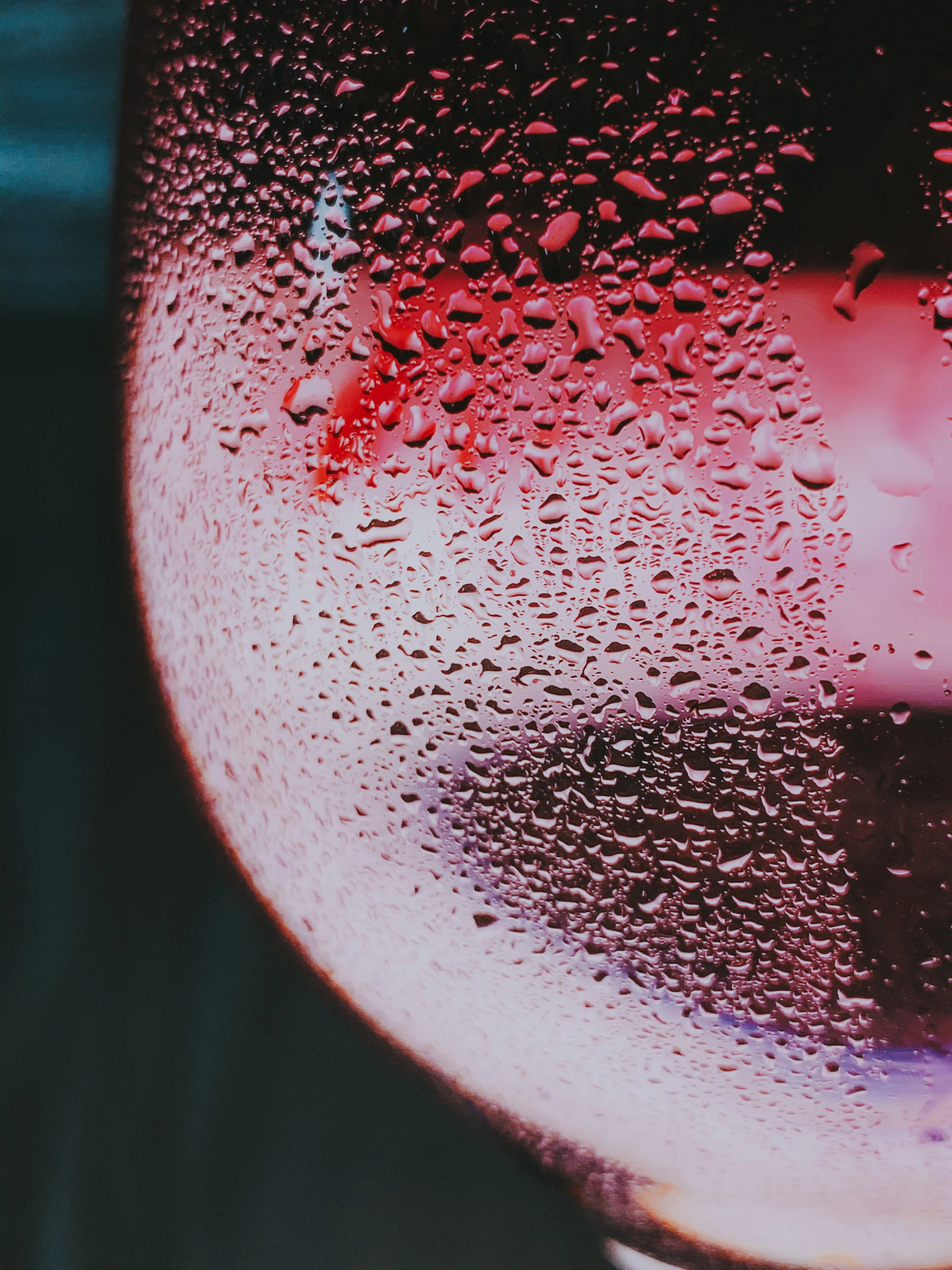 Red wine in a glass with droplets and dramatic red light